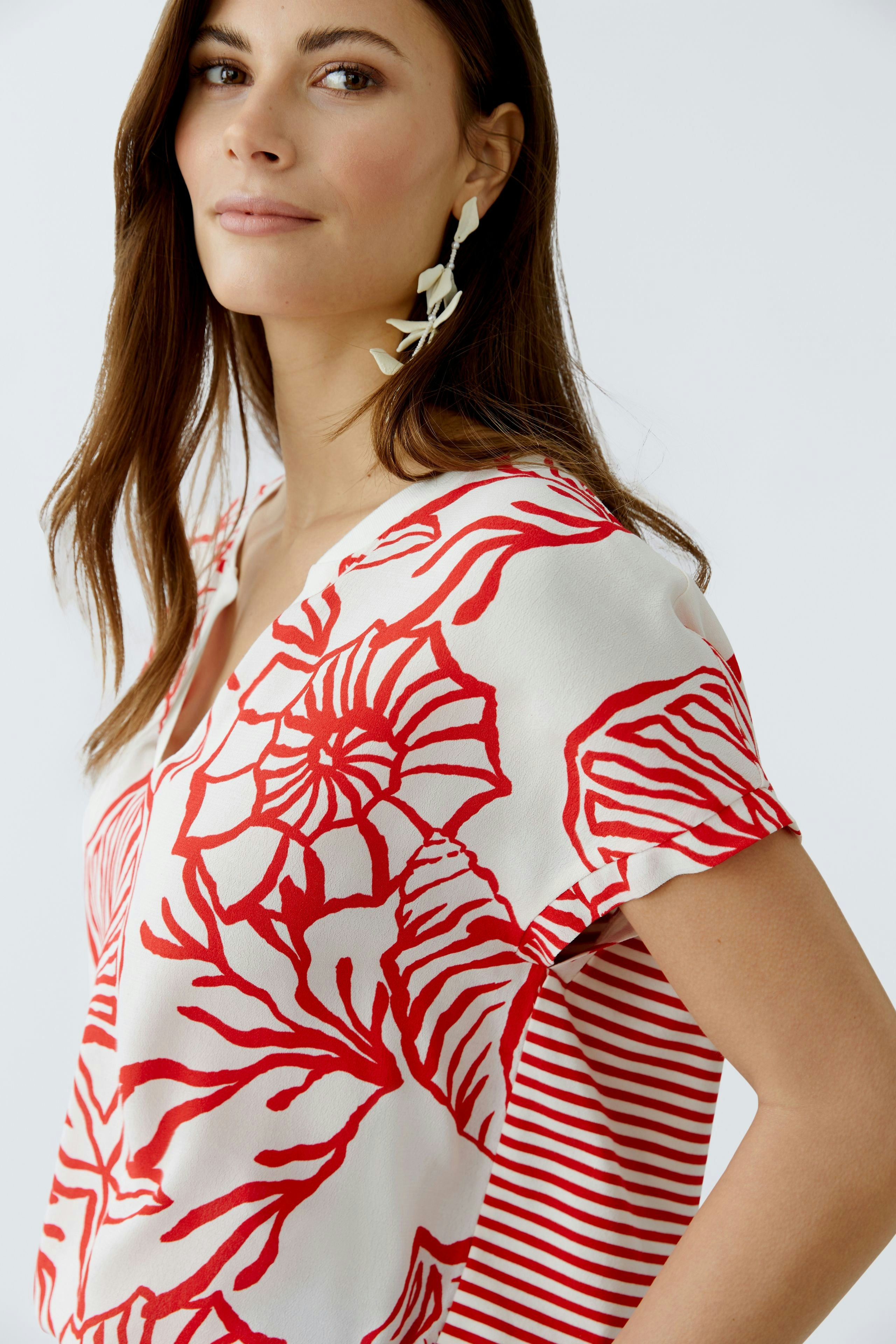 Casual women's blouse shirt with a floral pattern and striped sleeves, worn by a woman.