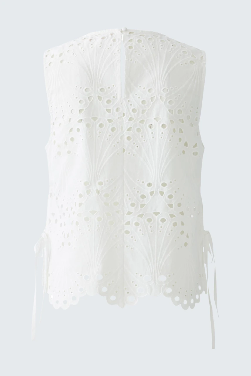 Stylish women's top: White sleeveless top with intricate cut-out details and adjustable ties at the sides.