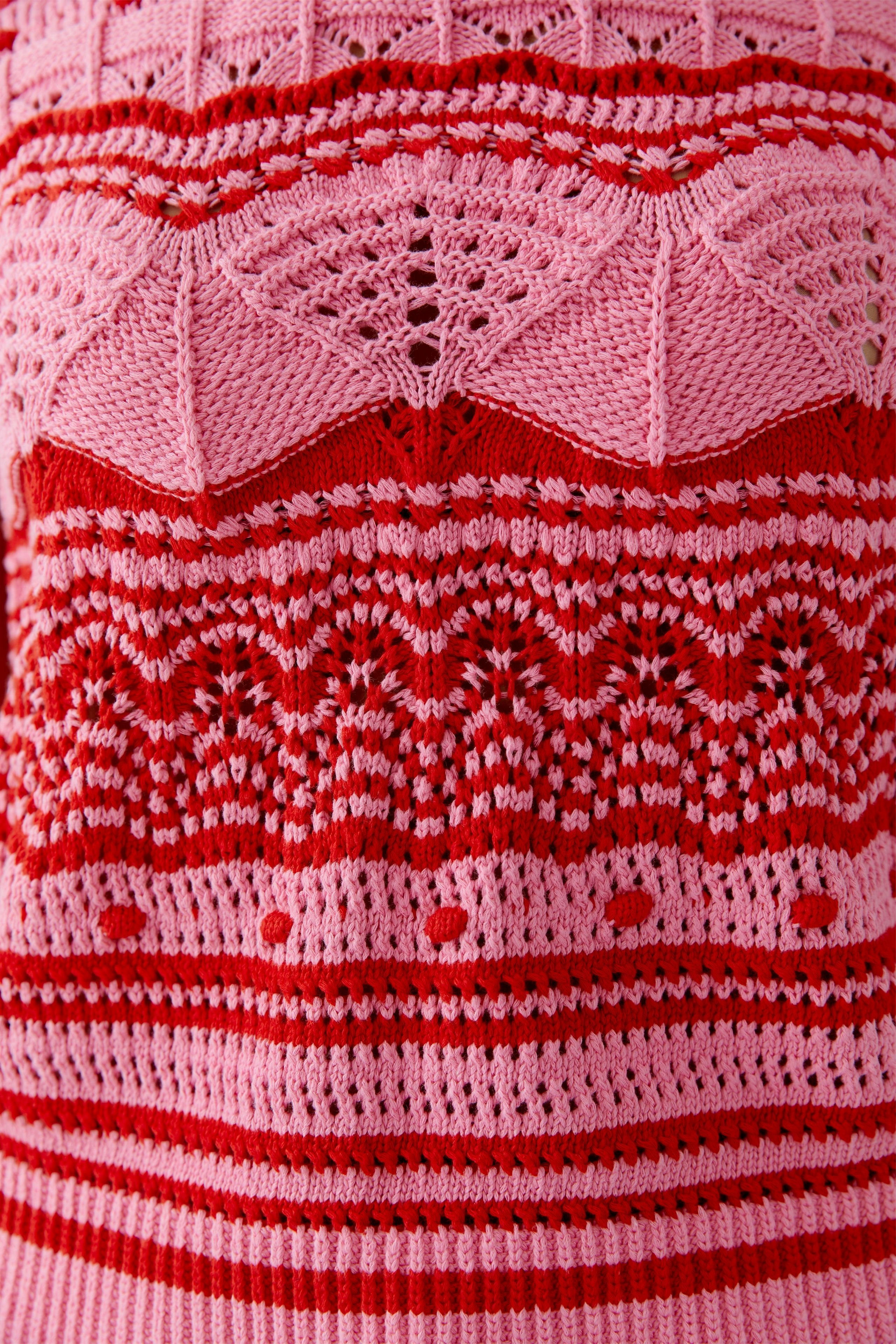 Buntes Damen-Top: Detailaufnahme eines gestrickten Tops in Pink- und Rottönen mit auffälligem Muster.