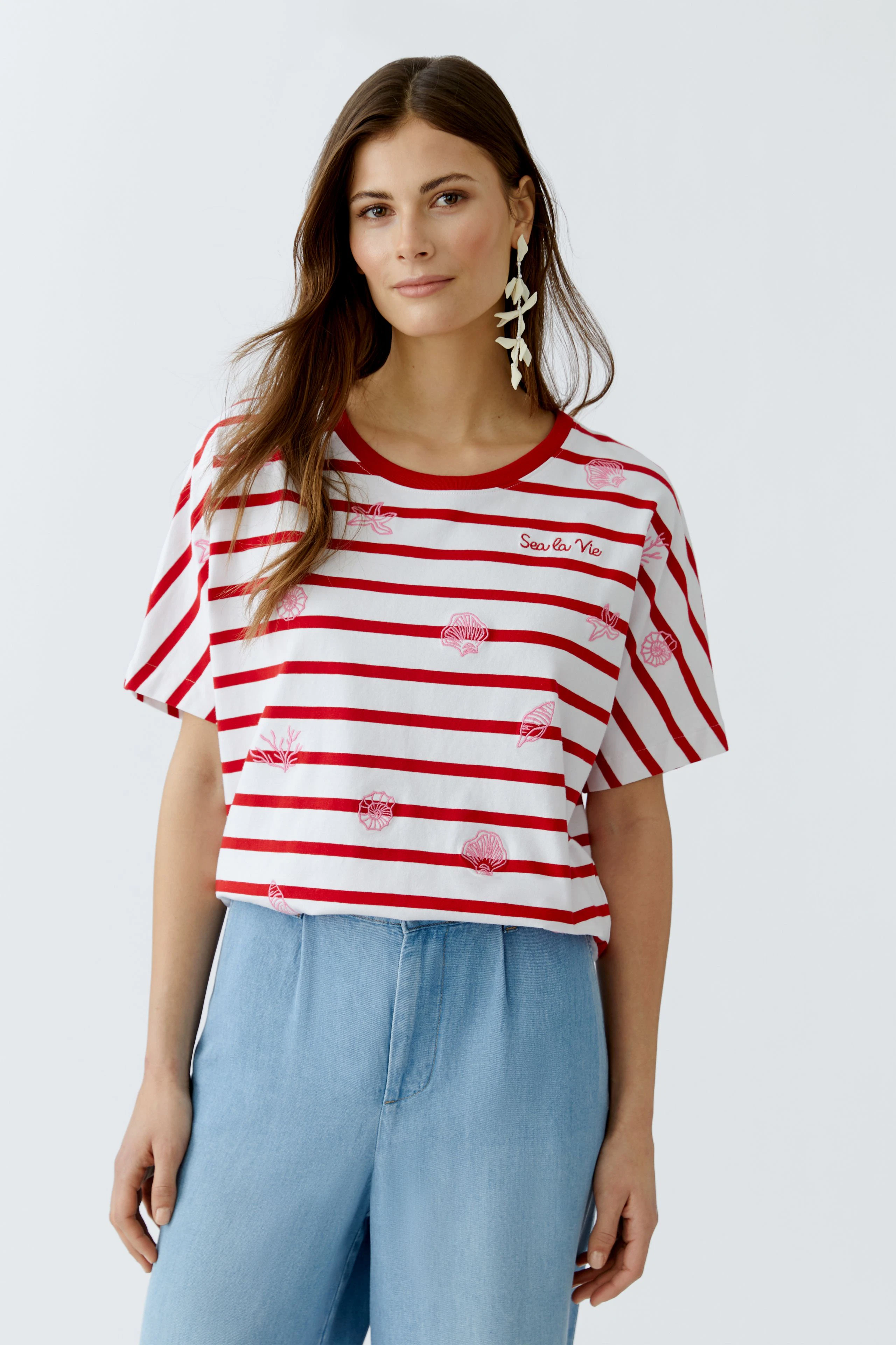 Lässiges Damen-T-Shirt: Frau trägt ein gestreiftes Shirt mit bunten Motiven und lockerer Passform.