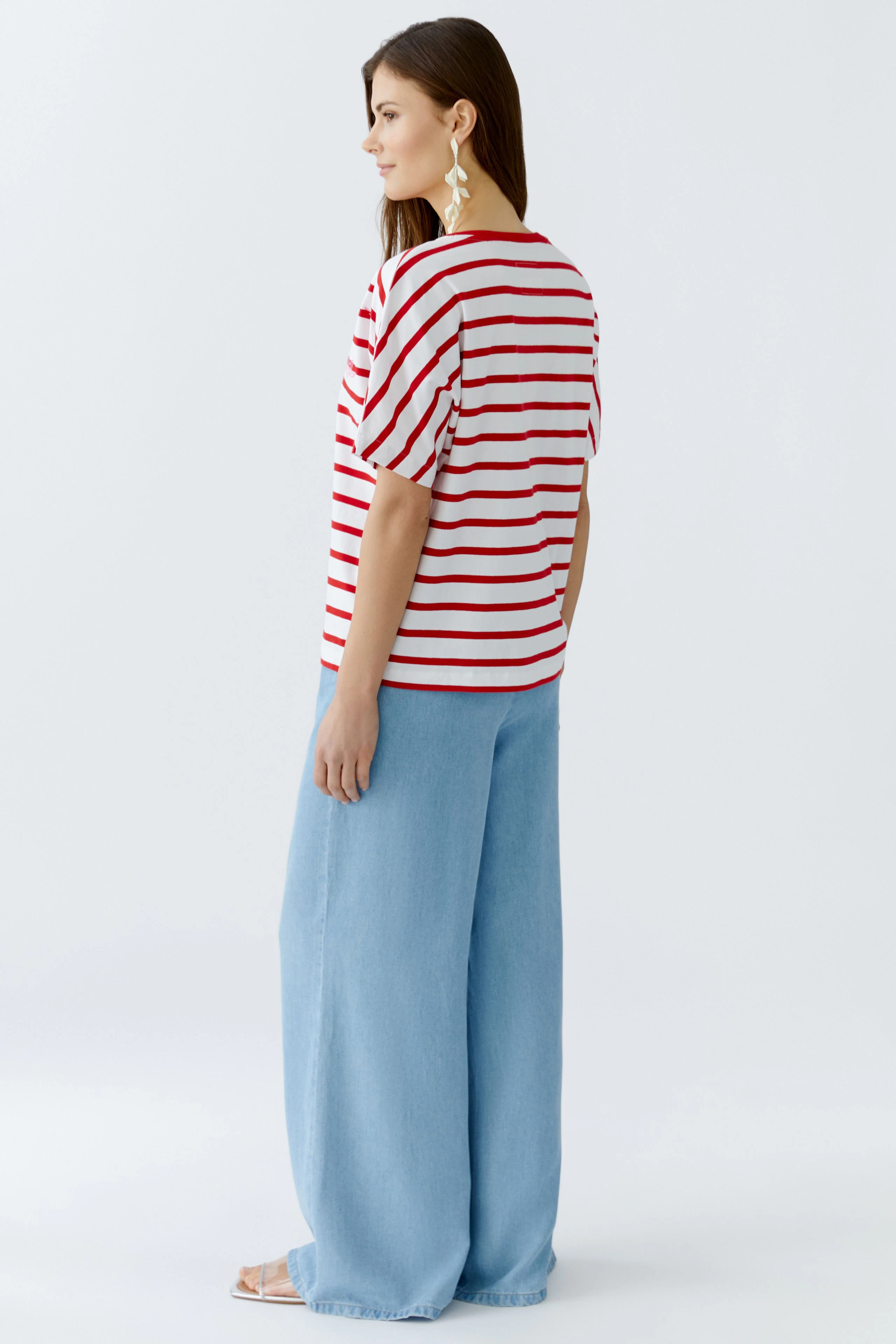 Damen-T-Shirt: Frau trägt ein gestreiftes T-Shirt in Rot und Weiß, kombiniert mit weiten Jeans.