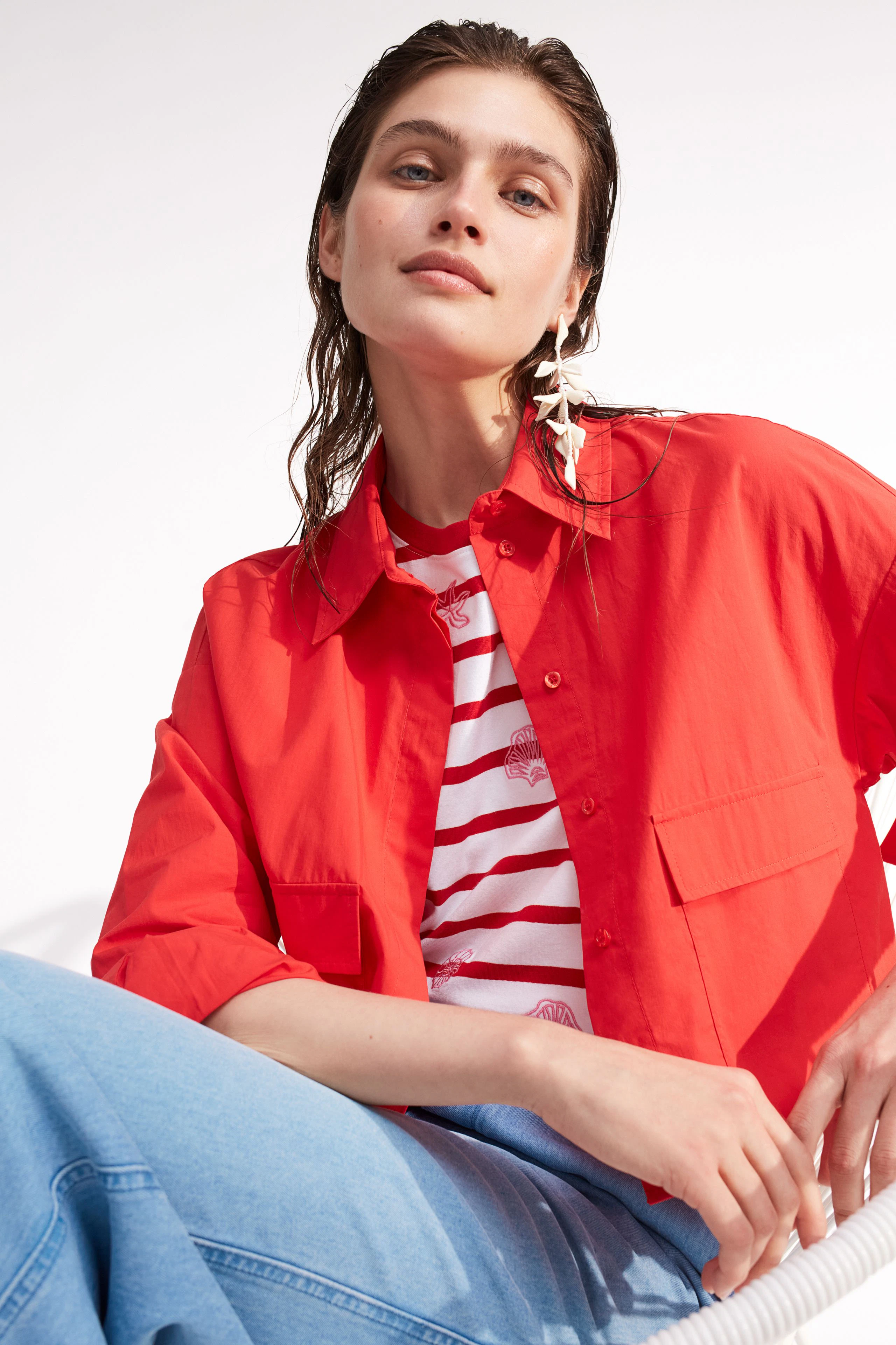 Damen-T-Shirt: Junge Frau in rot-weiß gestreiftem Shirt mit lässiger Jacke und entspannter Pose.