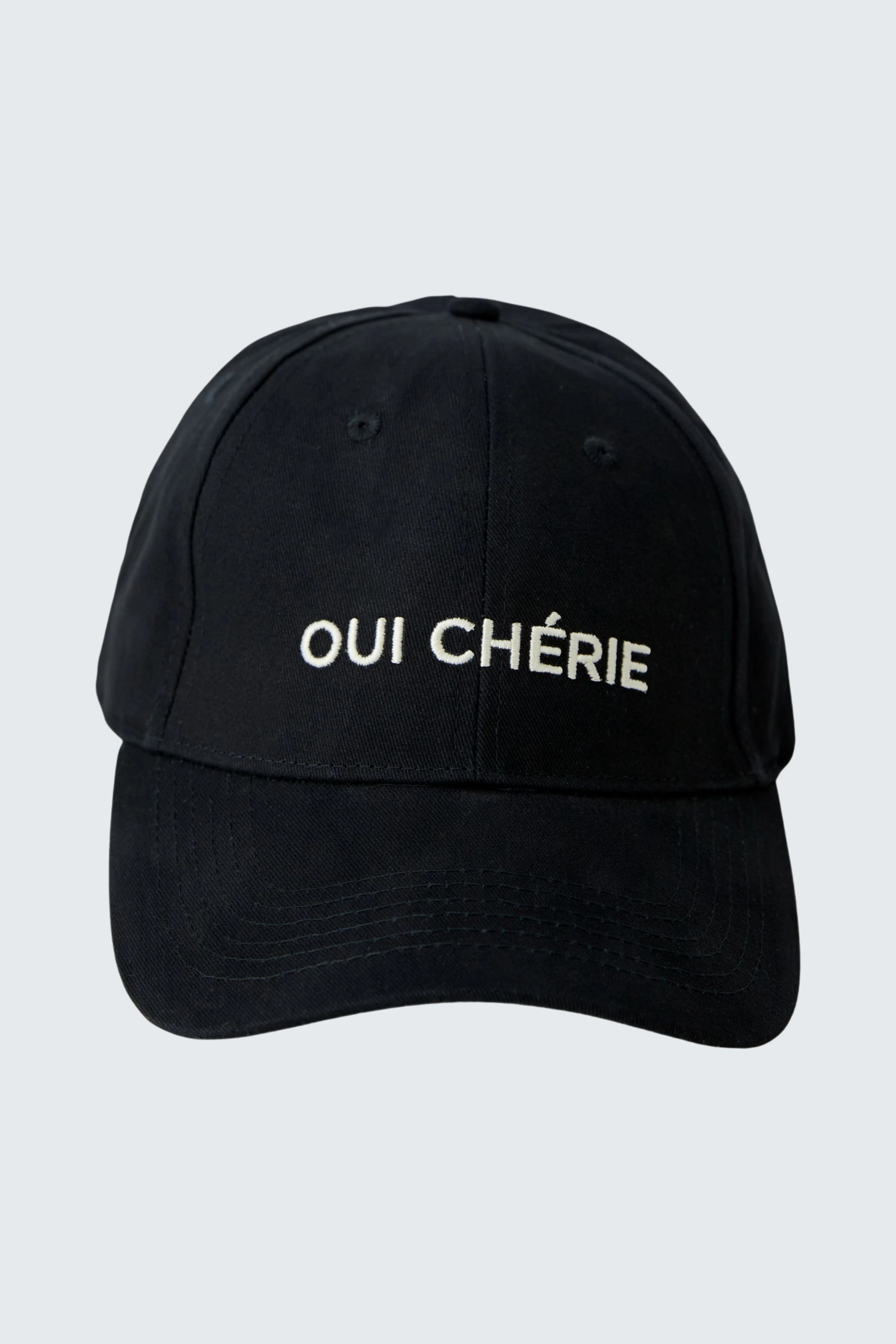 Schwarze Cap mit weißem Schriftzug 'OUI CHÉRIE', ideal für lässige Outfits.