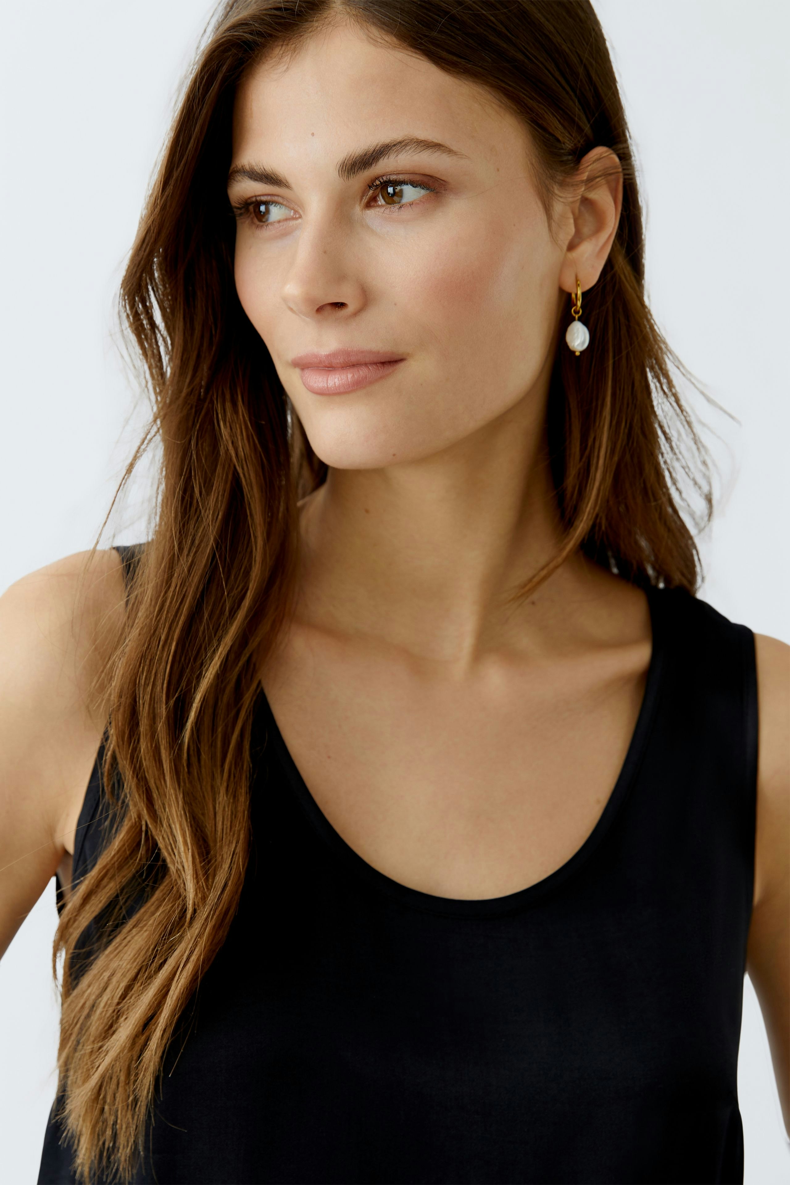 Schwarzes Damen-Top: Junge Frau mit schlichten Accessoires und natürlichem Look.