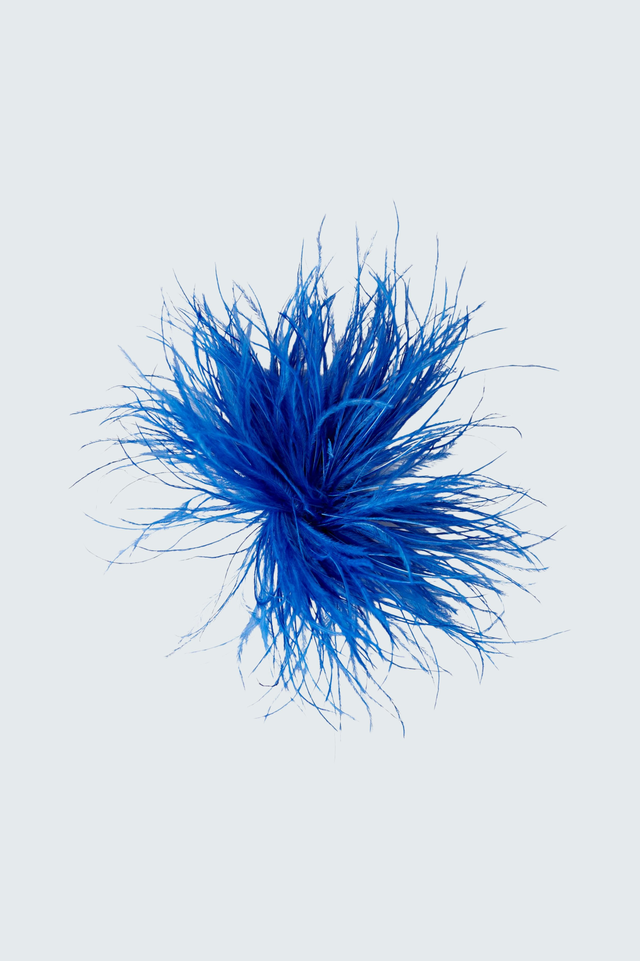 Flauschige blaue Accessoires: Ein dekoratives Accessoire in Form einer blauen Pompom für Damen.