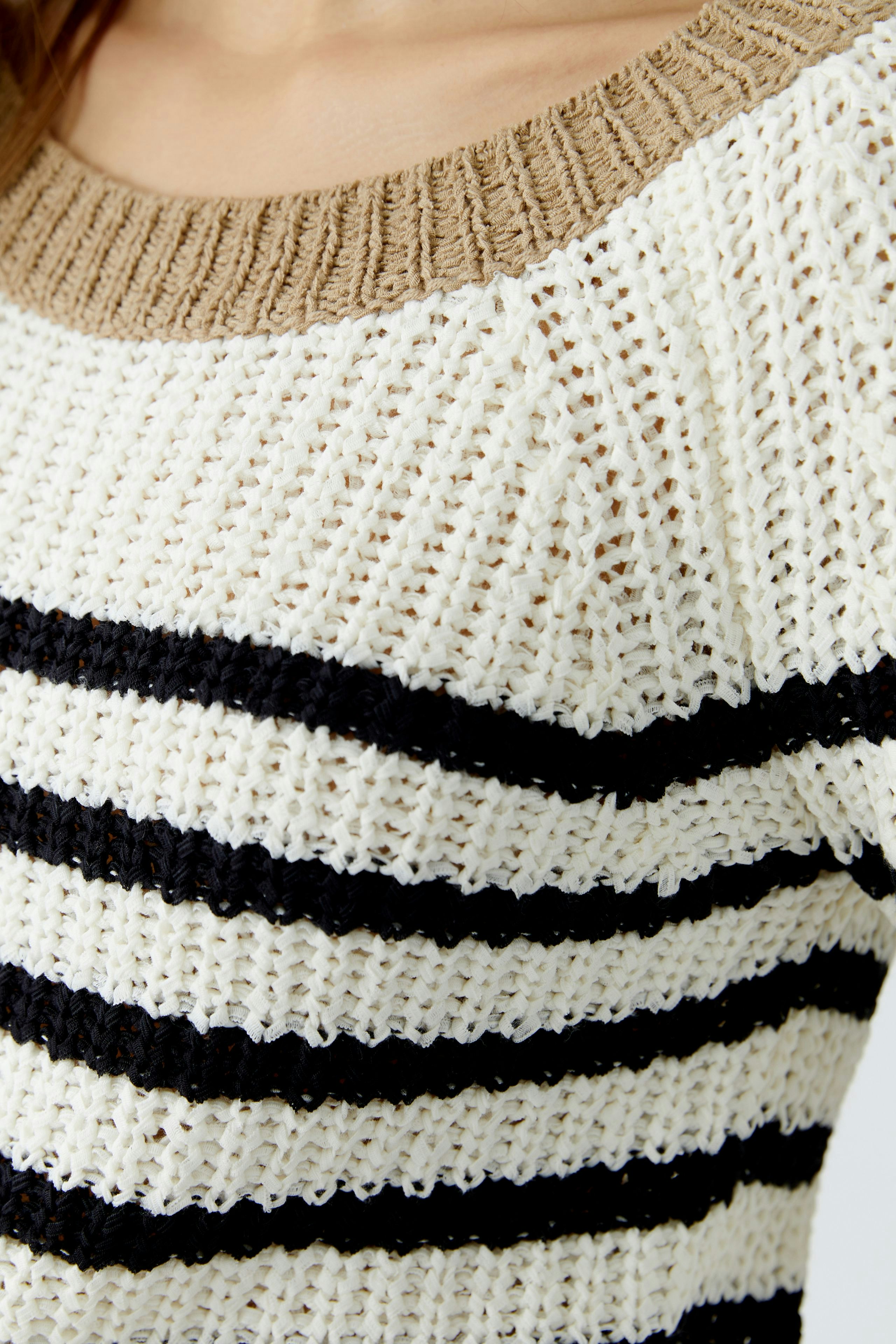 Casual women's pullover: Close-up of a woman in a striped knit pullover with a beige neckline.