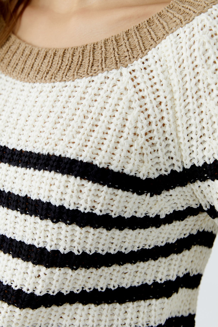 Damen-Pullover: Frau trägt einen gestreiften Pullover in Schwarz, Weiß und Beige mit weitem Rundhalsausschnitt.