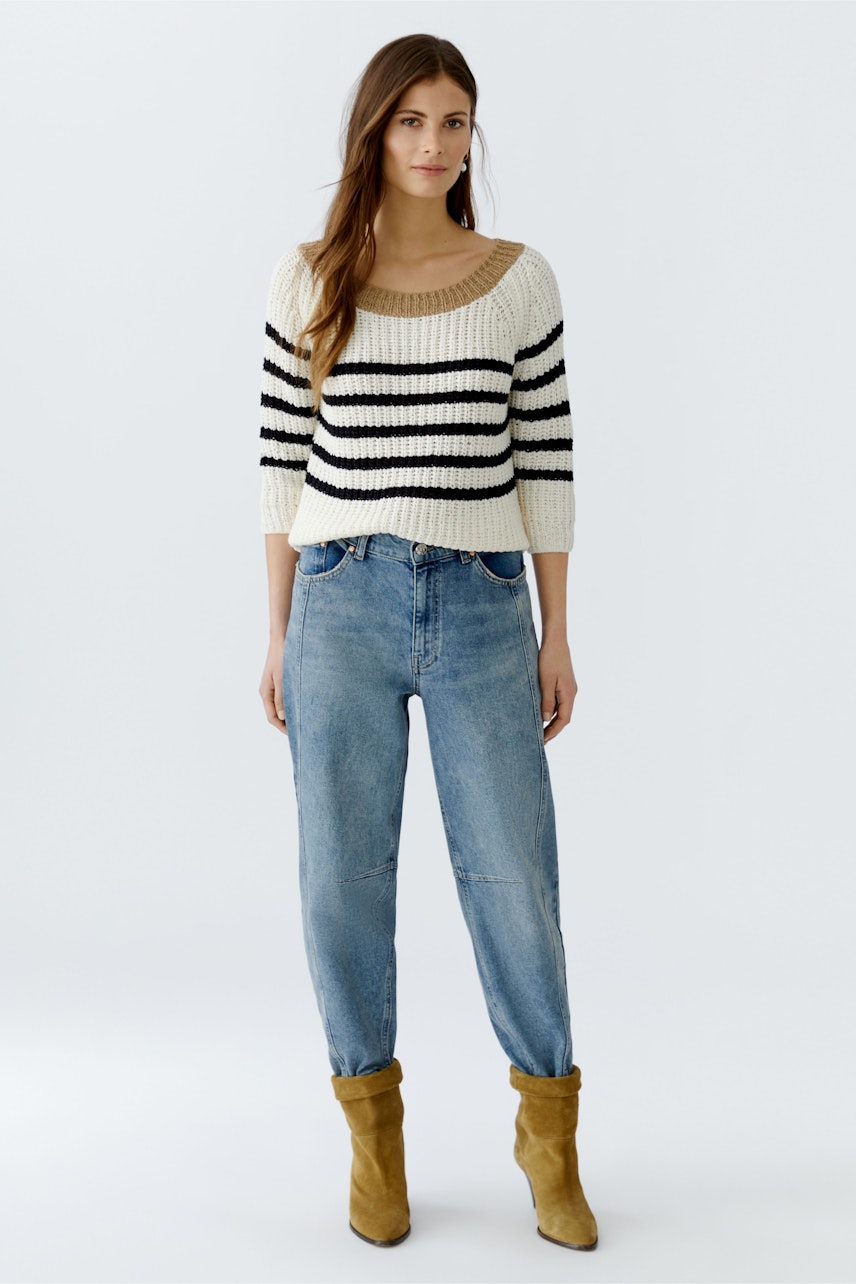Damen-Pullover: Junge Frau im gestreiften Strickpullover mit lässigen Jeans und Stiefeln.