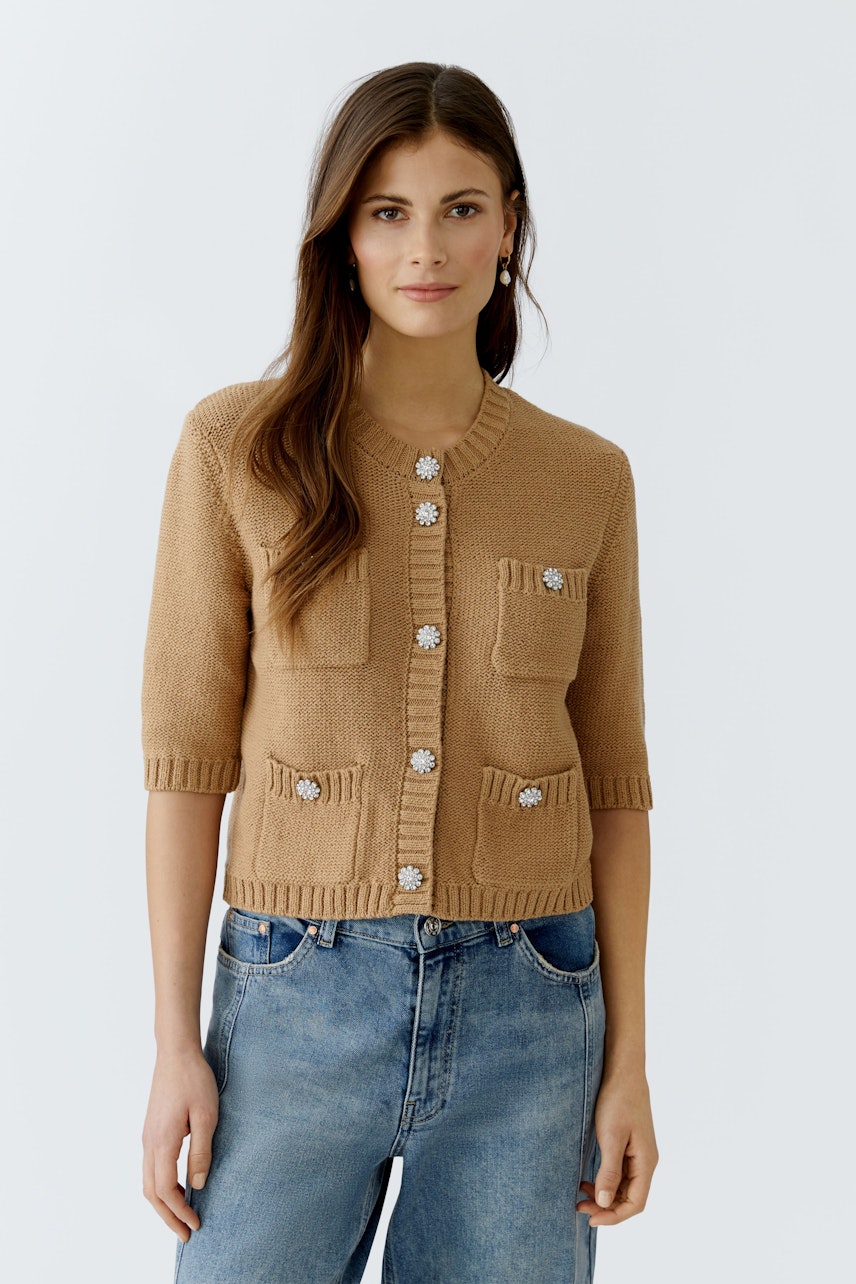 Bequeme Damen-Strickjacke: Frau in brauner Strickjacke mit Taschen und Knöpfen, kombiniert mit Jeans.