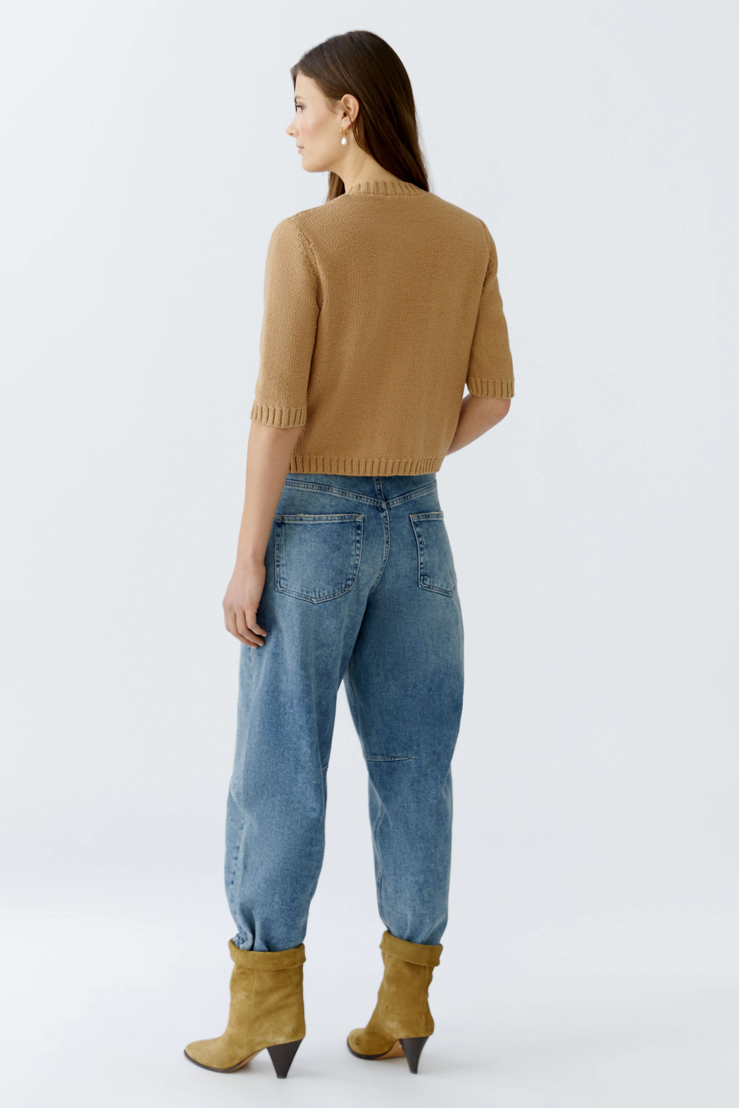 Casual women's cardigan: Woman in a short-sleeved beige cardigan paired with relaxed jeans.