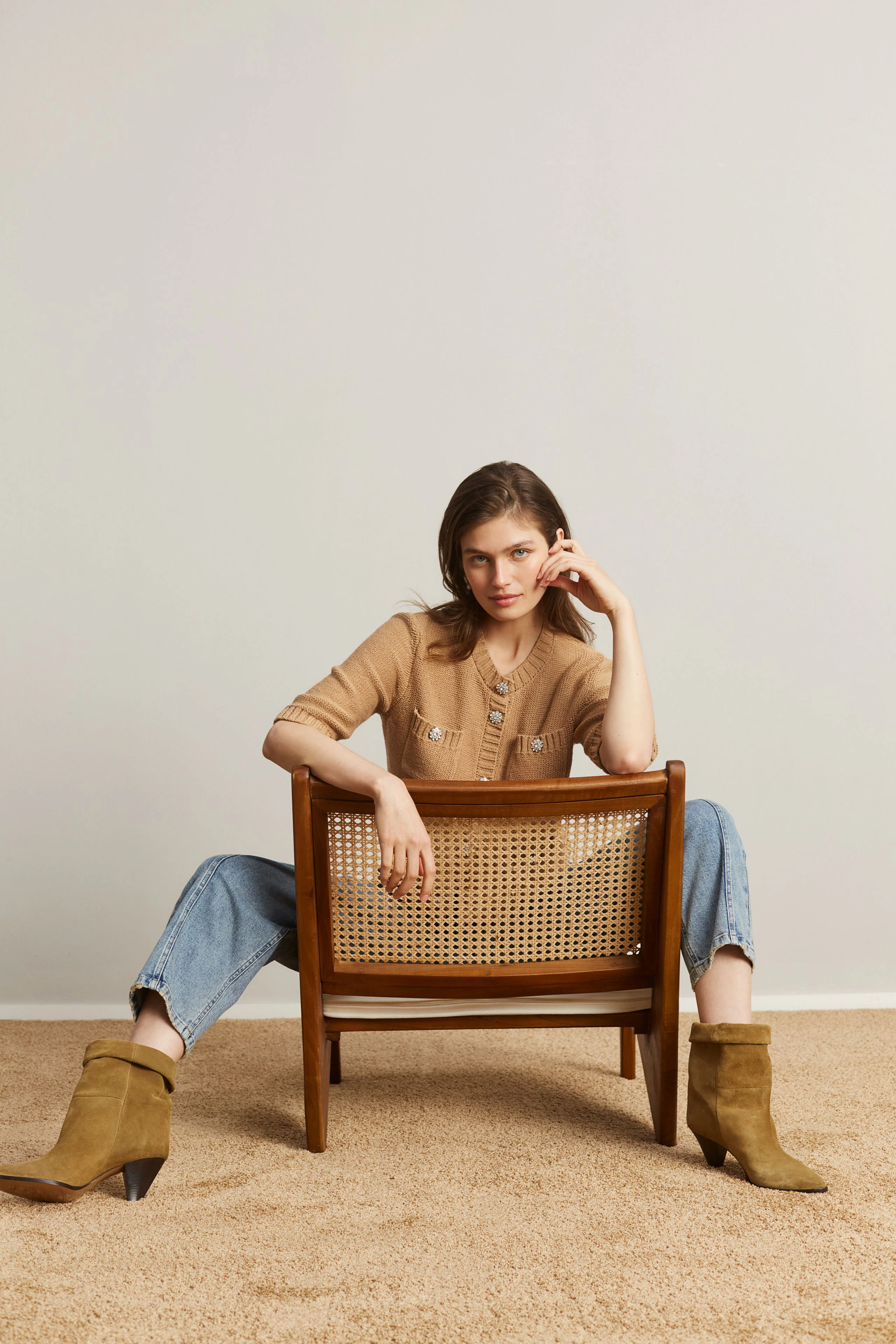 Casual women's cardigan: A woman in a beige cardigan with pockets sits confidently on a chair.
