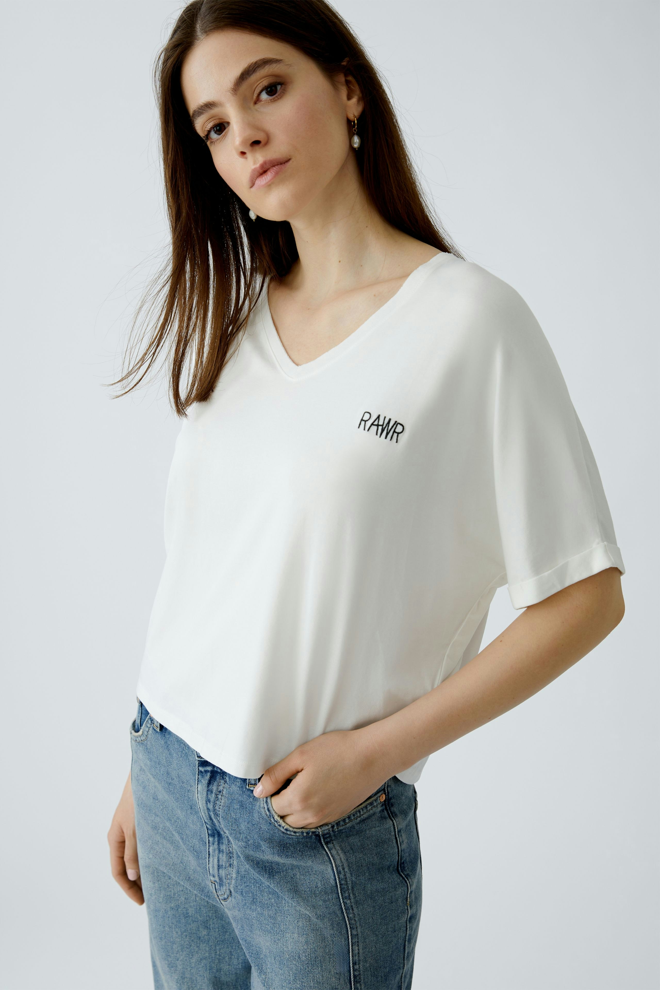 Damen-T-Shirt in Weiß: Junge Frau trägt ein lässiges T-Shirt mit V-Ausschnitt und Logo.