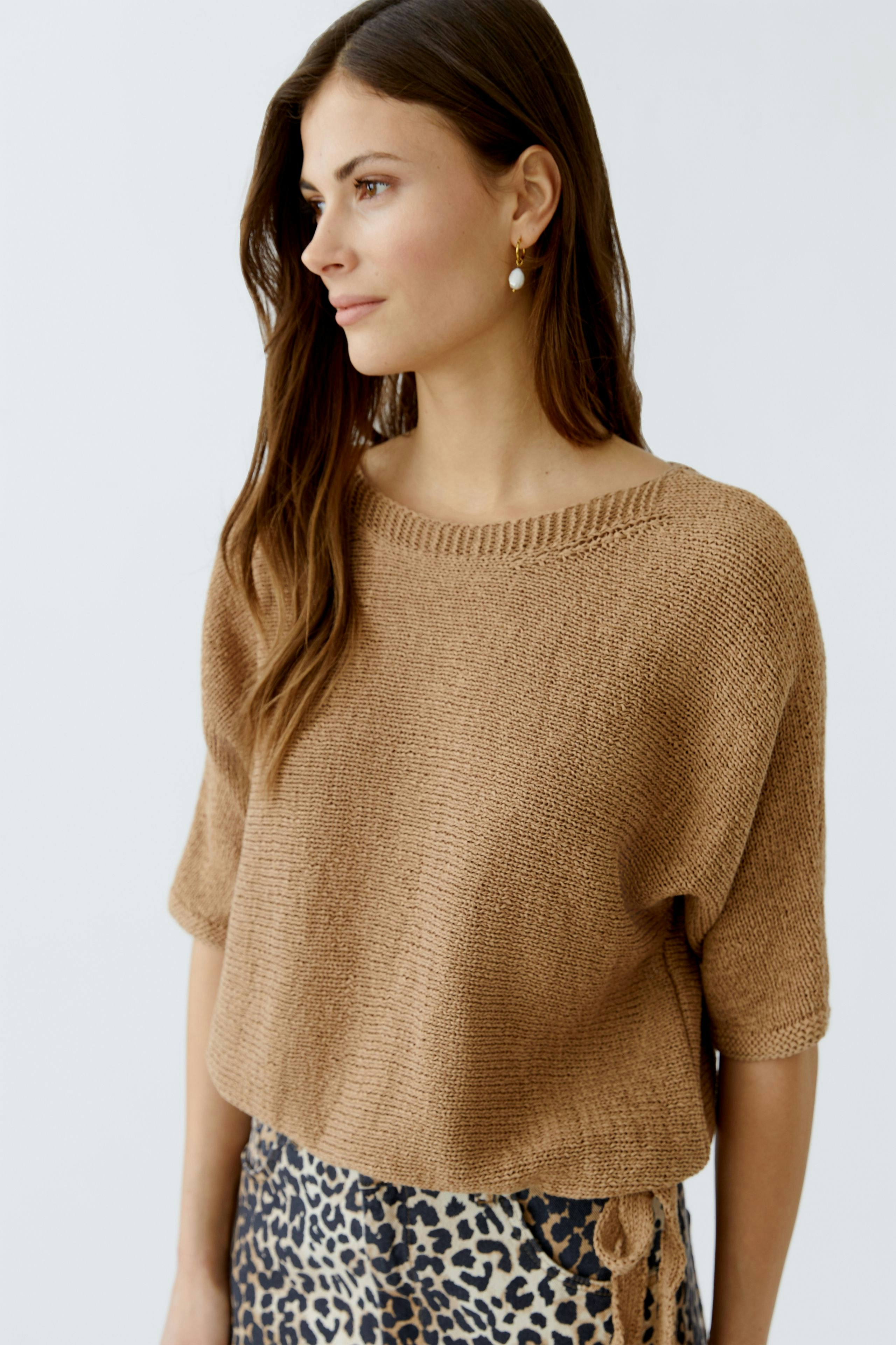 Casual women's pullover: Young woman in a brown knitted pullover paired with a leopard print skirt.