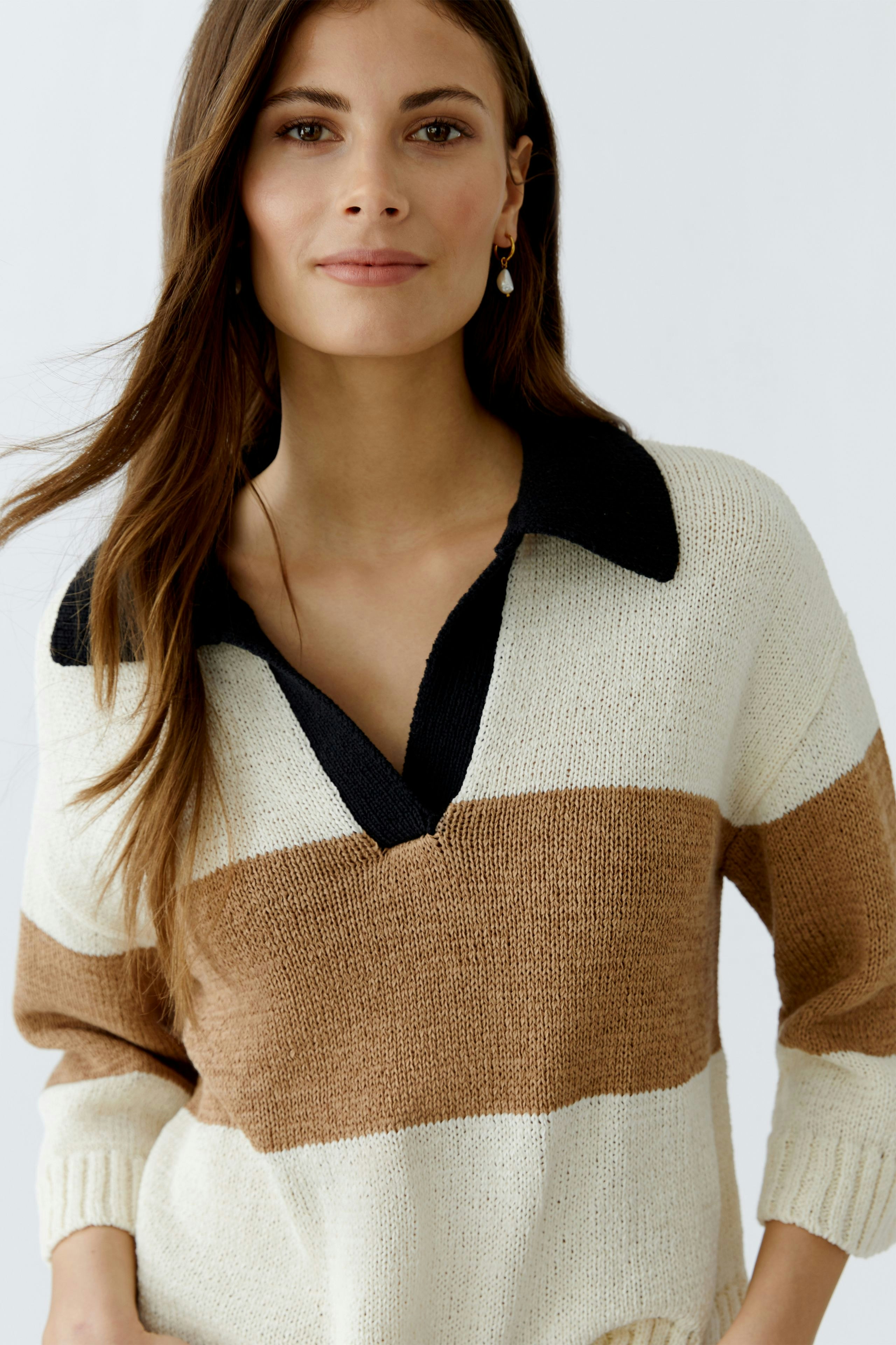 Casual women's pullover: Young woman in a striped pullover with a collar, smiling confidently.
