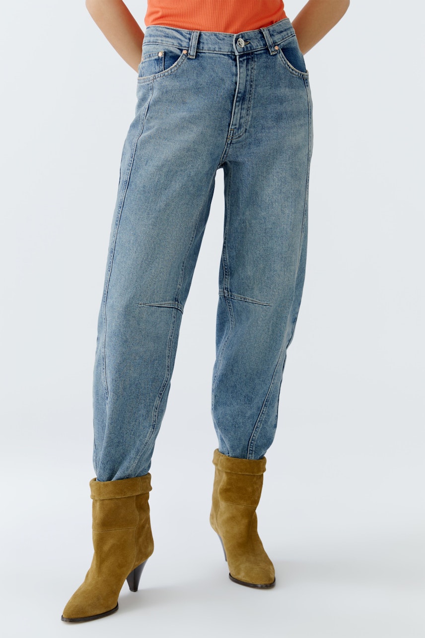 Casual women's jeans: A woman in light blue barrel jeans with a relaxed fit and pockets.