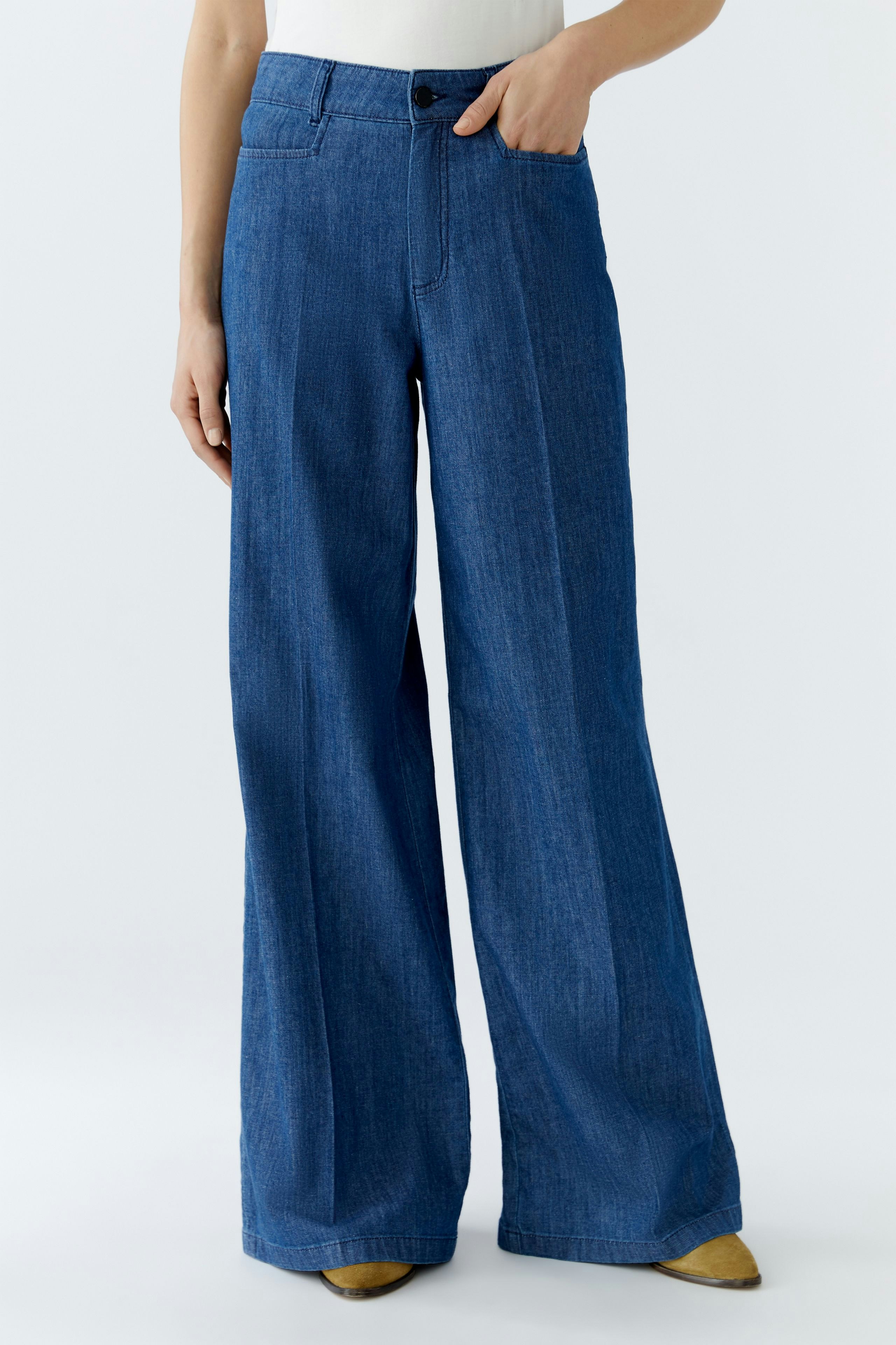 Casual women's pants: A woman in wide-leg denim pants stands confidently, showcasing a relaxed style.