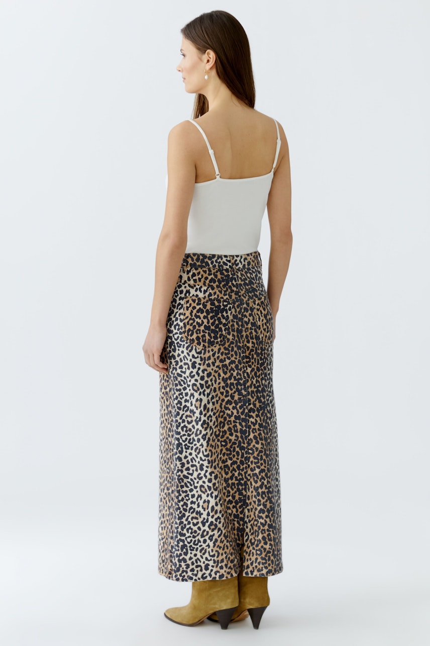 Damen-Jeansrock: Frau in einem Jeansrock mit Leopardenmuster und schlichten Top von hinten.