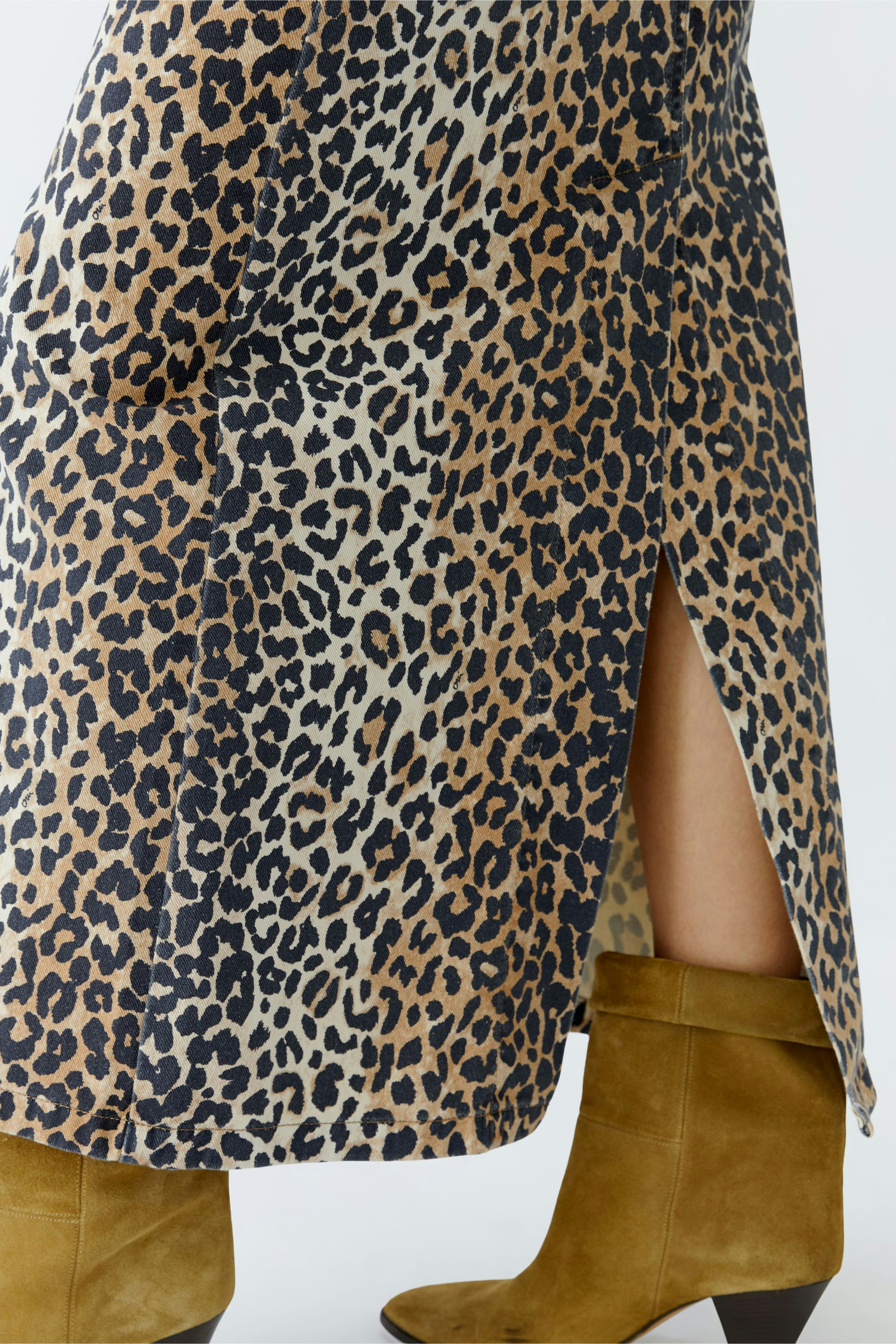 Leopard print denim skirt: A woman showcases a stylish jeans skirt with a side slit and trendy boots.