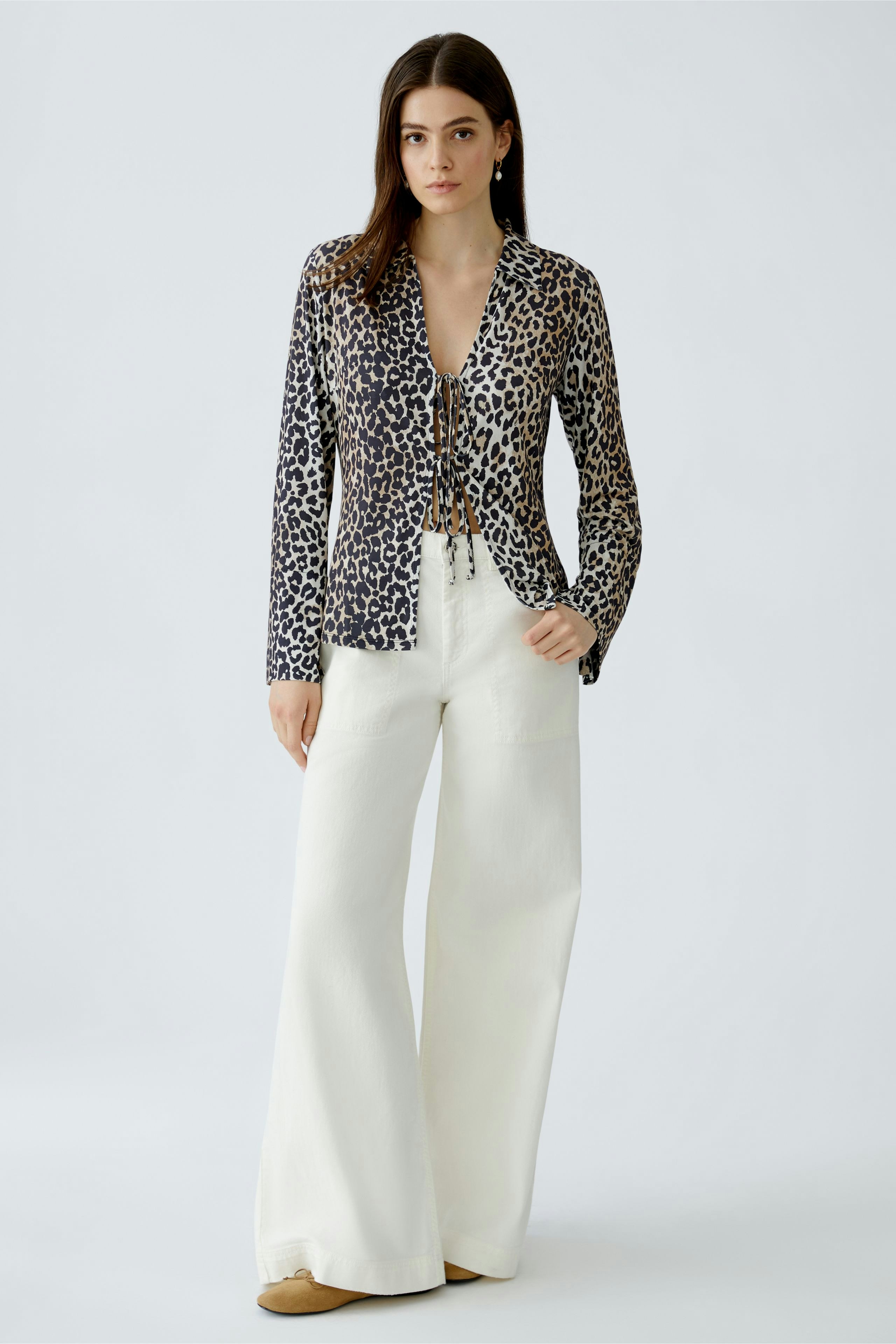 Leopardenbluse: Frau in transparenter Bluse mit Krawatte und weiten weißen Hosen.