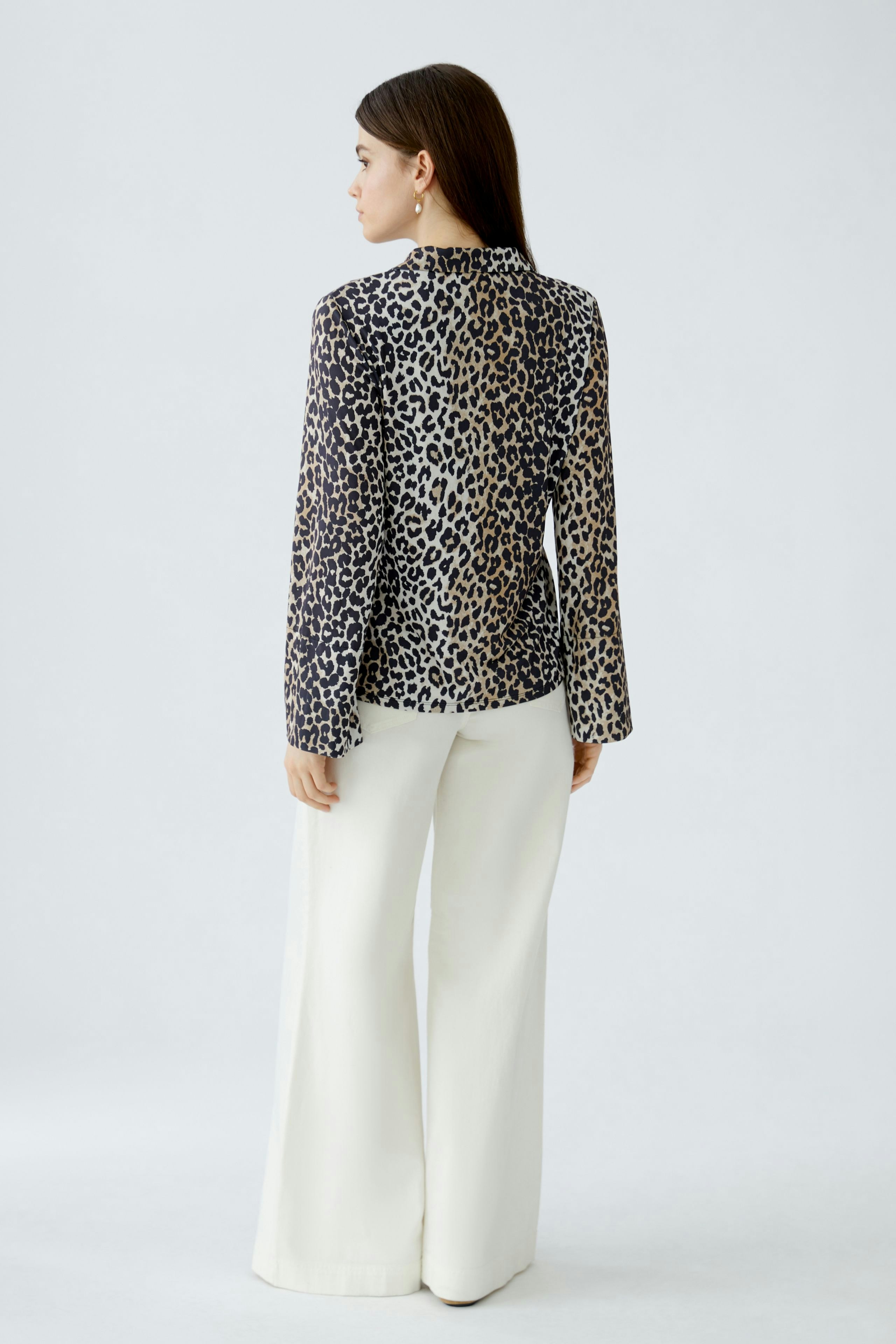 Damen-Bluse im Leo-Design: Frau trägt die Bluse mit langen Ärmeln und lässigen, weißen Hosen.