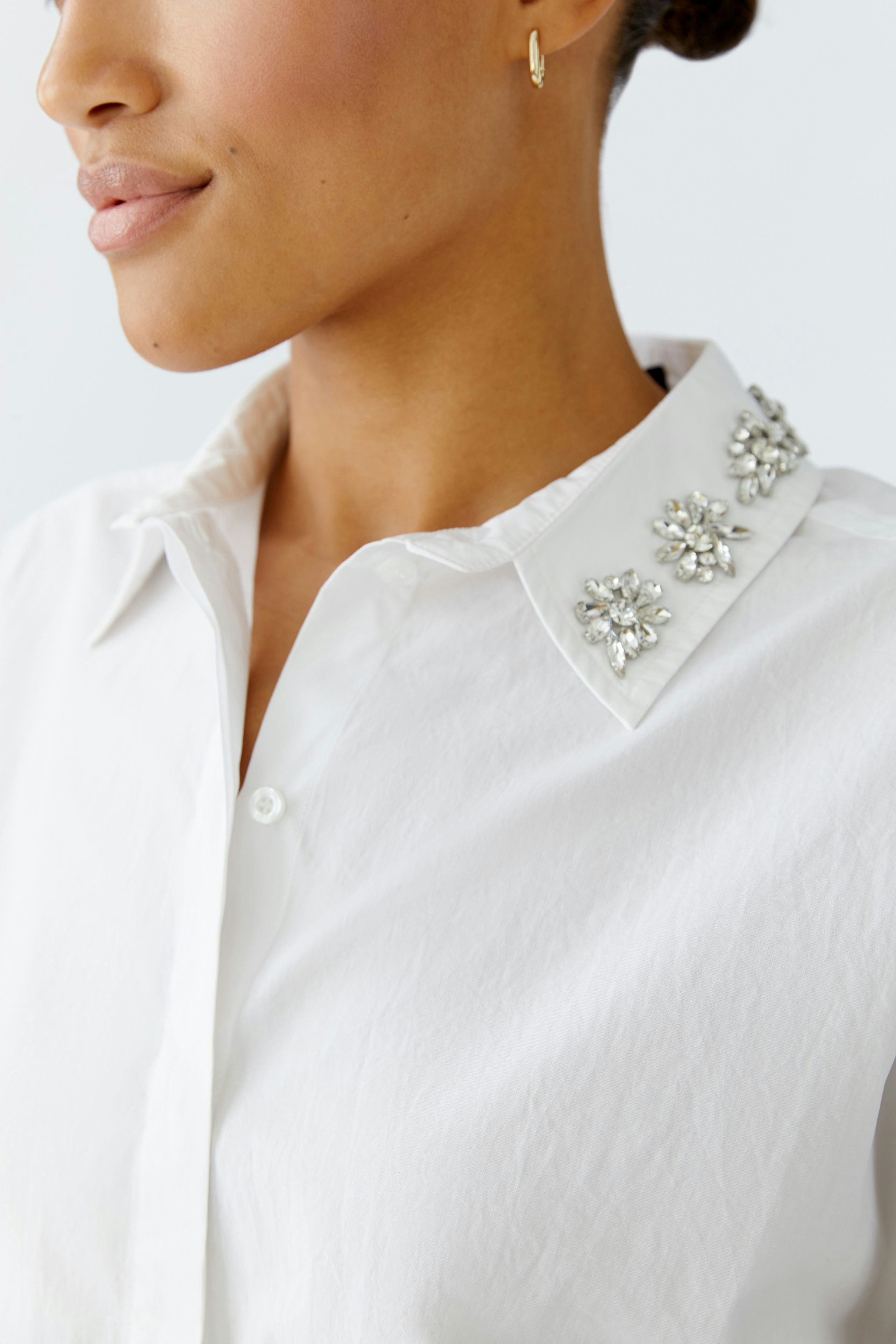 Moderne Damen-Bluse: Frau mit schlichter Bluse und dekorativem Kragen blickt in die Kamera.