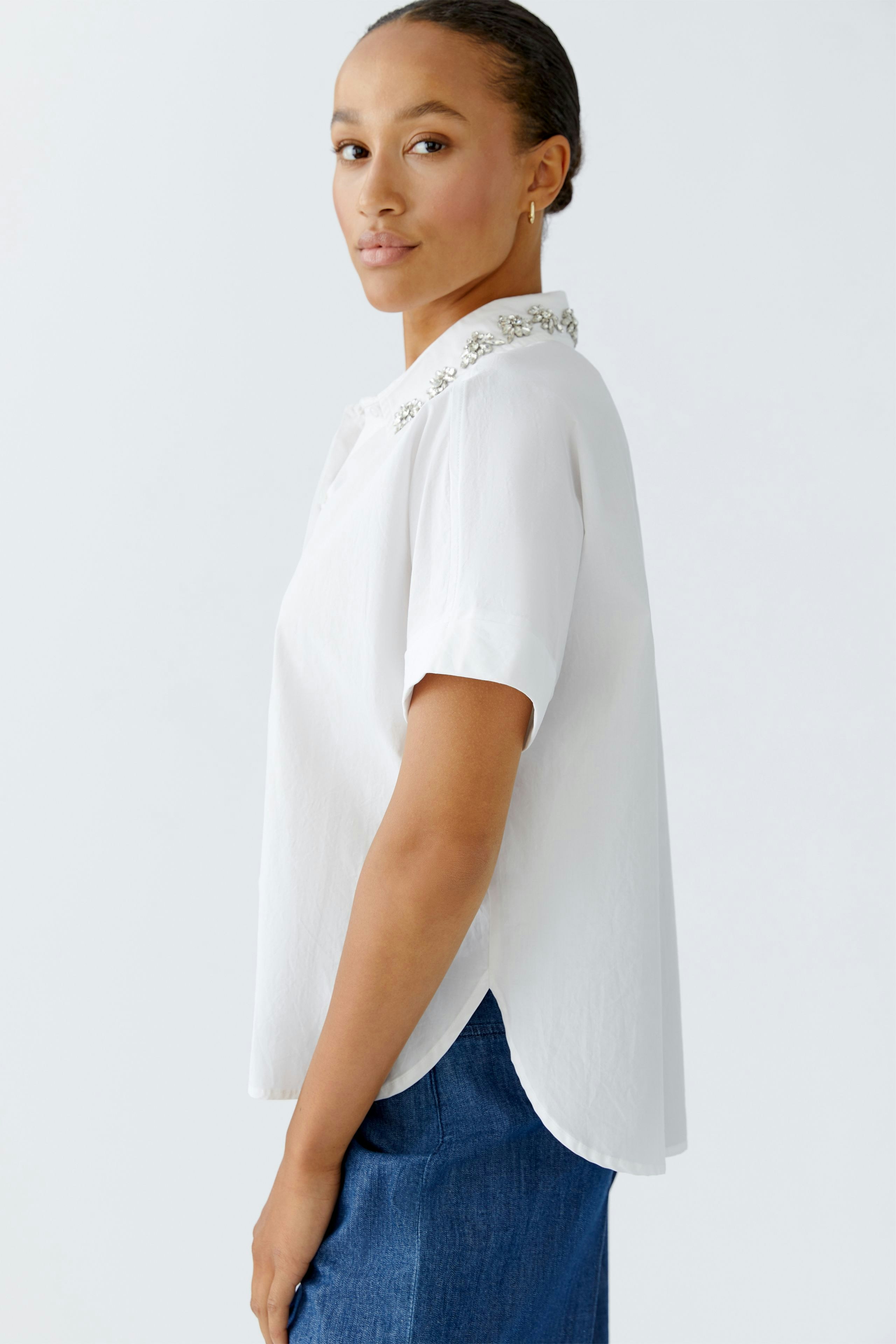 Moderne Damen-Bluse: Frau in weißer Bluse mit dekorativem Kragen und lässigem Look.