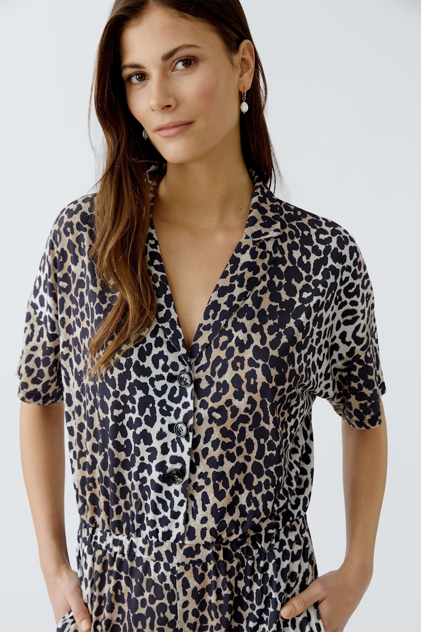 Damen-Jumpsuit: Frau in einem lässigen, gemusterten Jumpsuit mit kurzen Ärmeln und Knopfleiste.