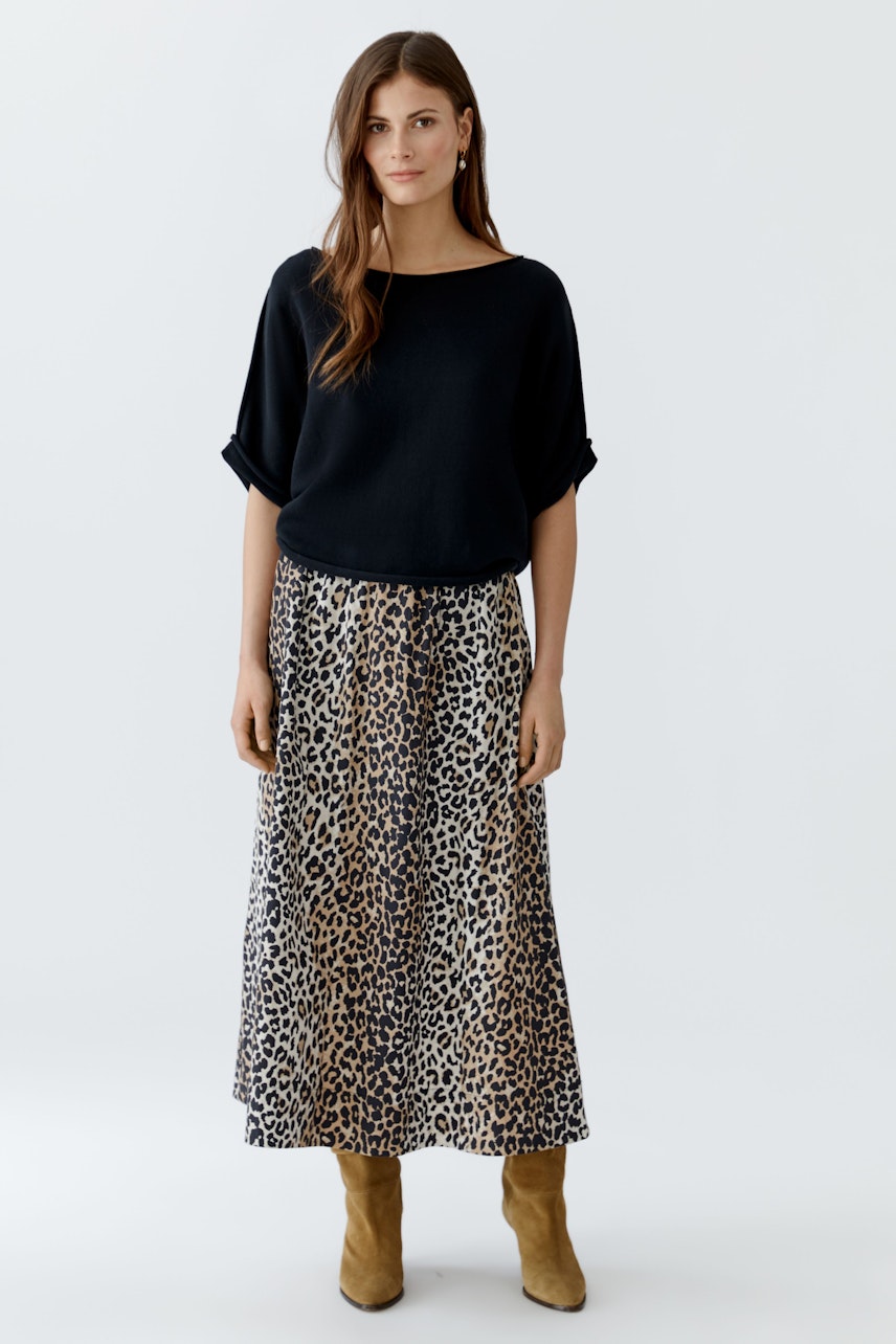 Damen-Pullover: Frau in schwarzem, lässigem Pullover mit weitem Schnitt und animalischem Rock.