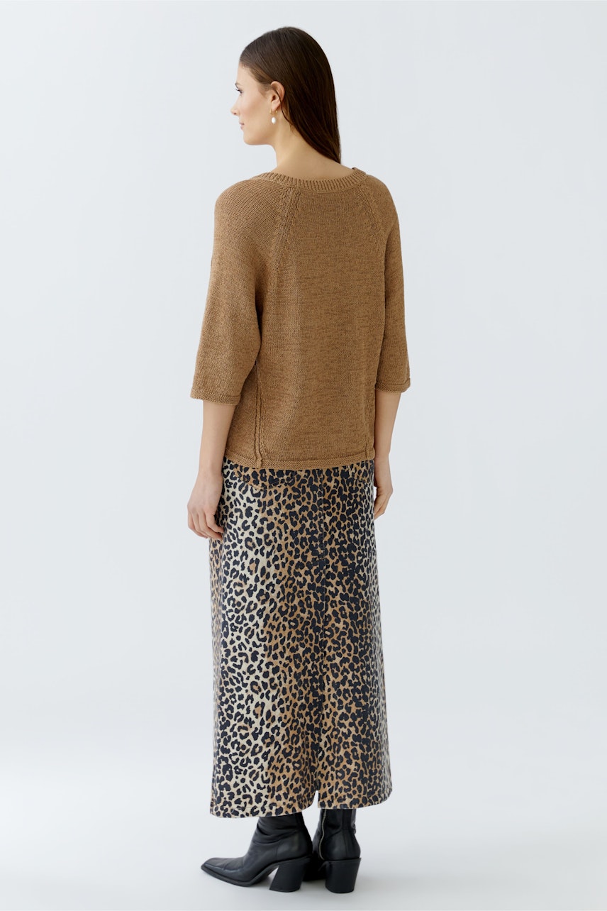 Damen-Pullover: Frau mit braunem Pullover und gemusterter Maxi-Rock von hinten.