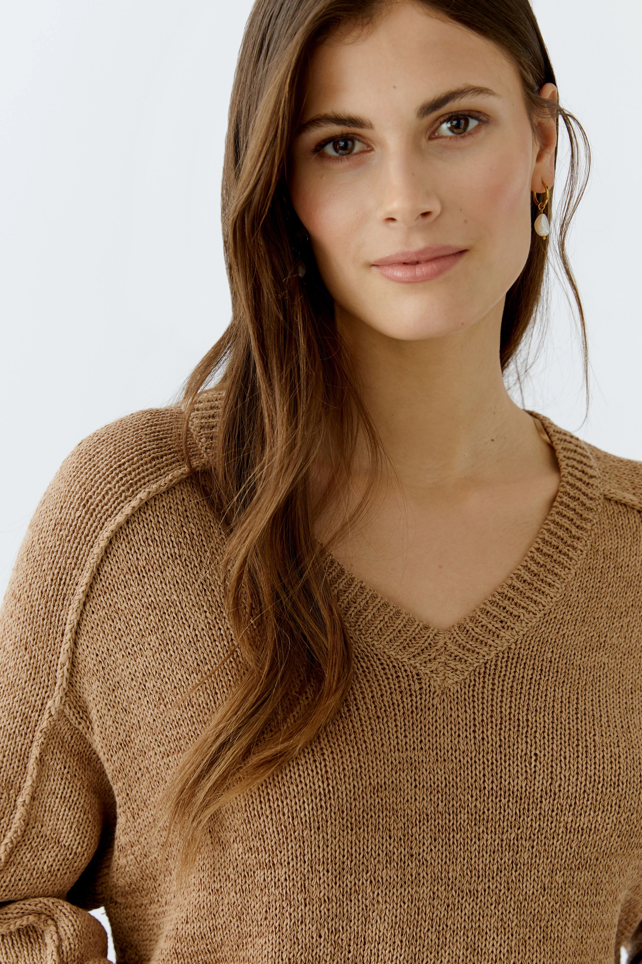 Casual women's pullover: A woman in a cozy brown V-neck pullover with a relaxed fit.