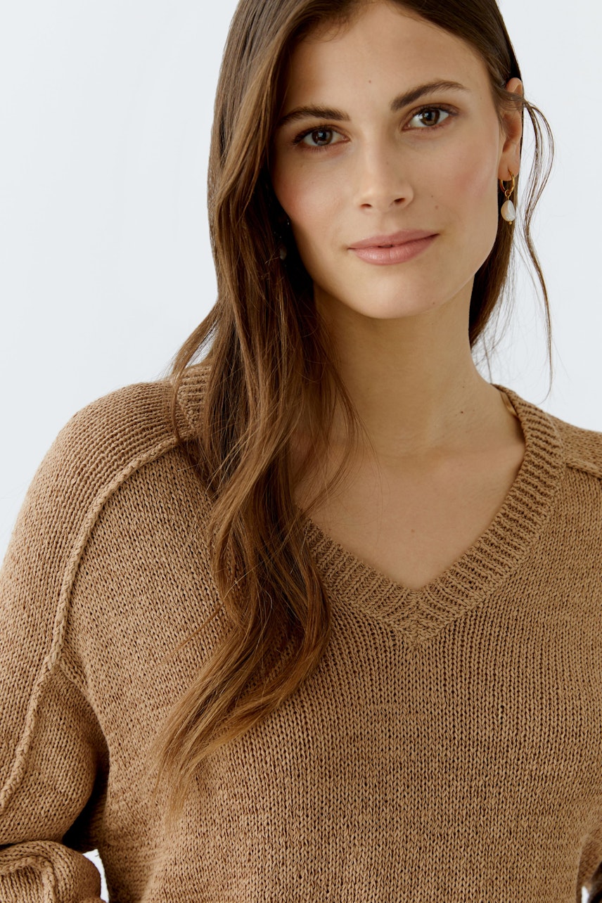 Damen-Pullover: Junge Frau im braunen V-Pullover mit lässigem Schnitt und feiner Strickstruktur.
