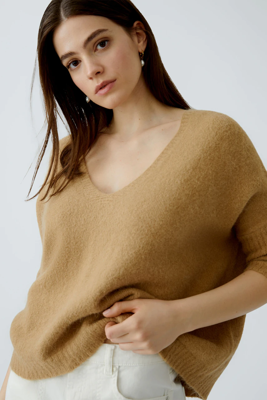 Bequemer Damen-Pullover in Beige mit V-Ausschnitt, lässig getragen von einer Frau.