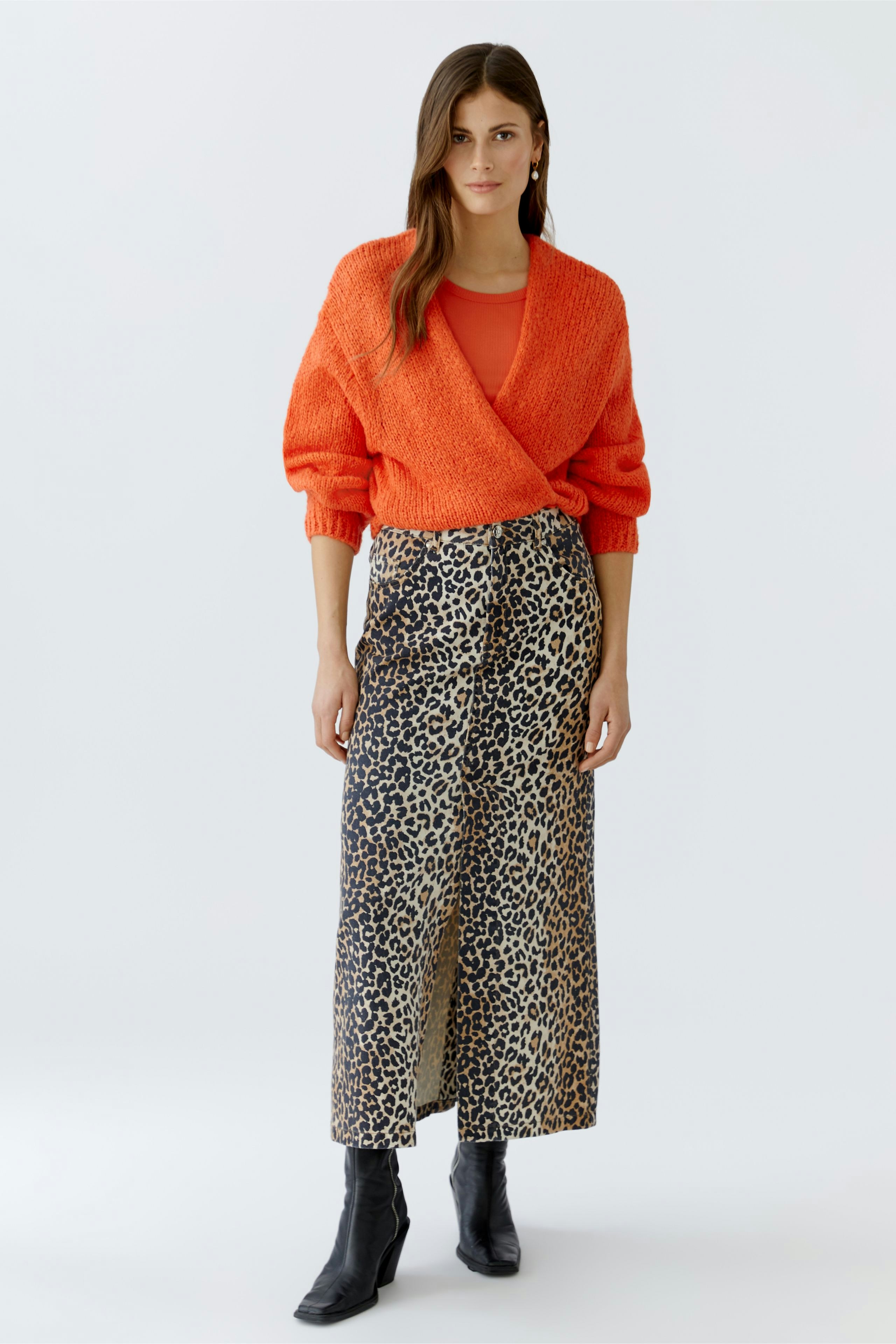 Damen-Strickjacke: Frau in orangefarbener Strickjacke mit lässigem Schnitt und animalischem Rock.