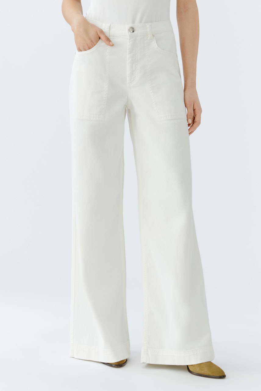 Flared jeans: A woman wearing white flared jeans with pockets, styled casually.