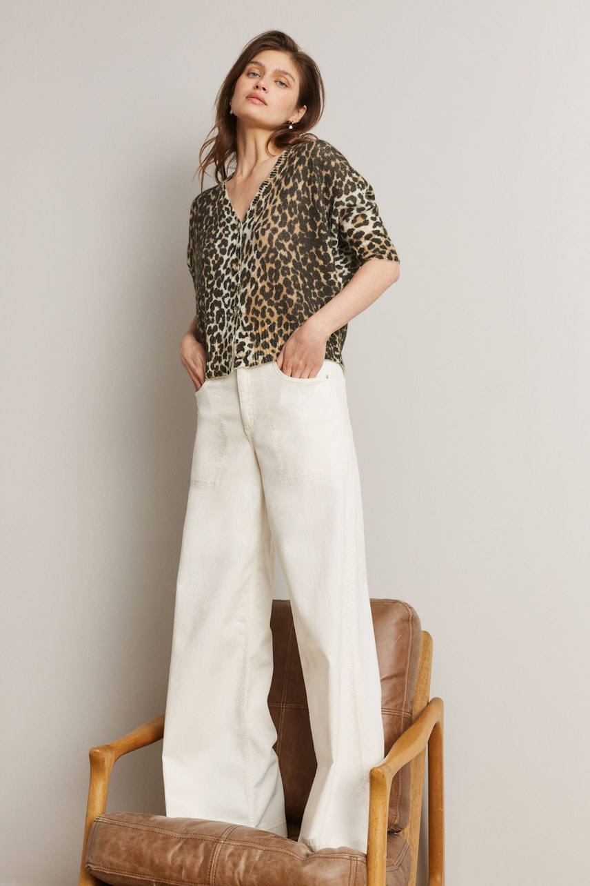 Flared jeans: Woman in a stylish outfit with a leopard print top and wide-leg flared jeans.