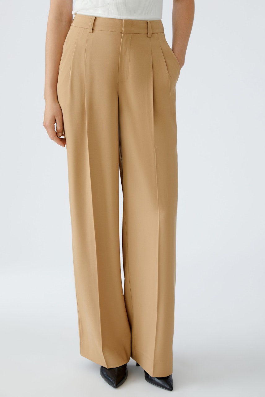 Chic women's pleated trousers in beige, featuring a relaxed fit and side pockets.