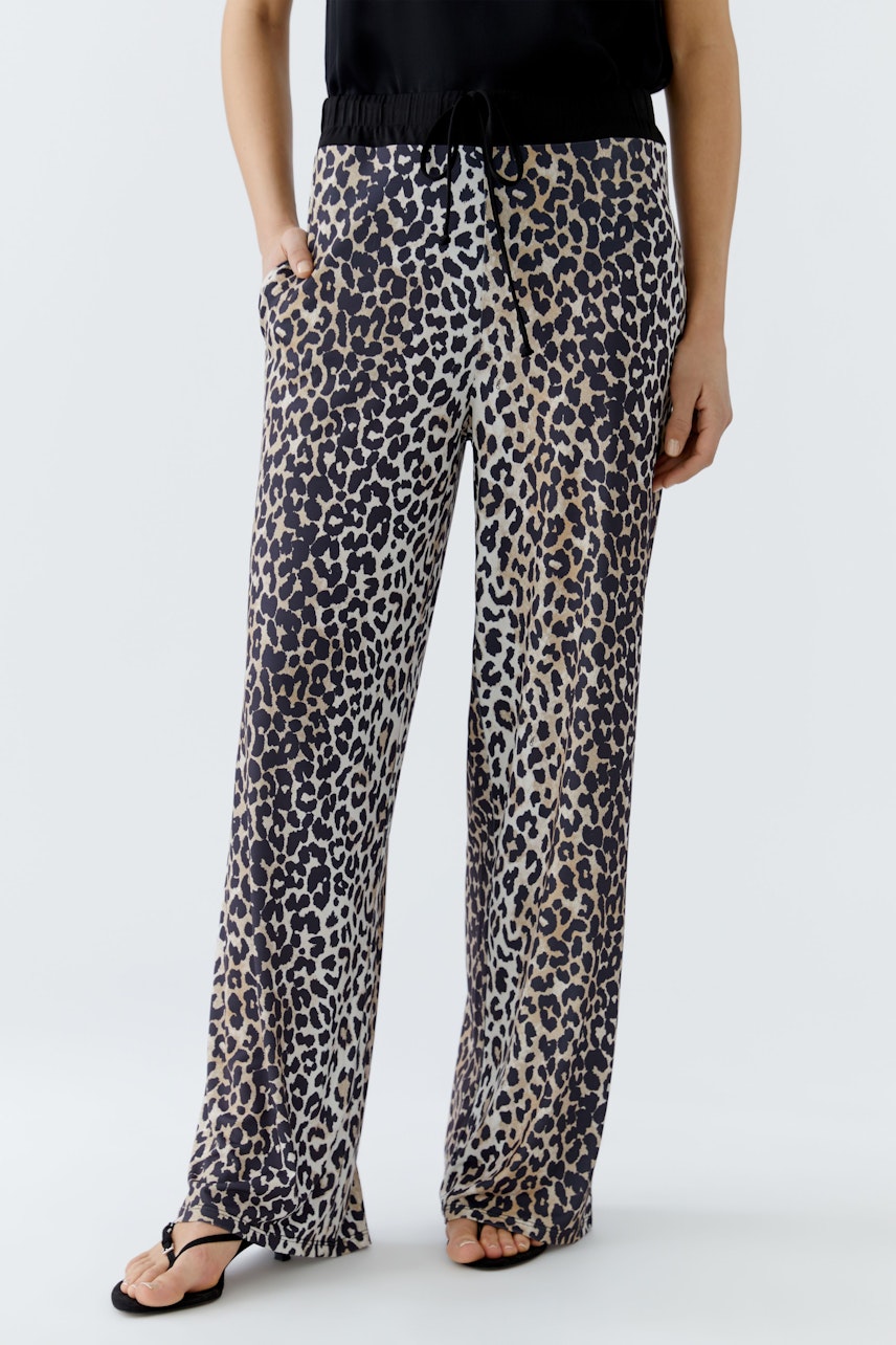 Bequeme Damen-Hose im Leo-Design: Frau trägt lässige, weite Hose mit elastischem Bund und Taschen.
