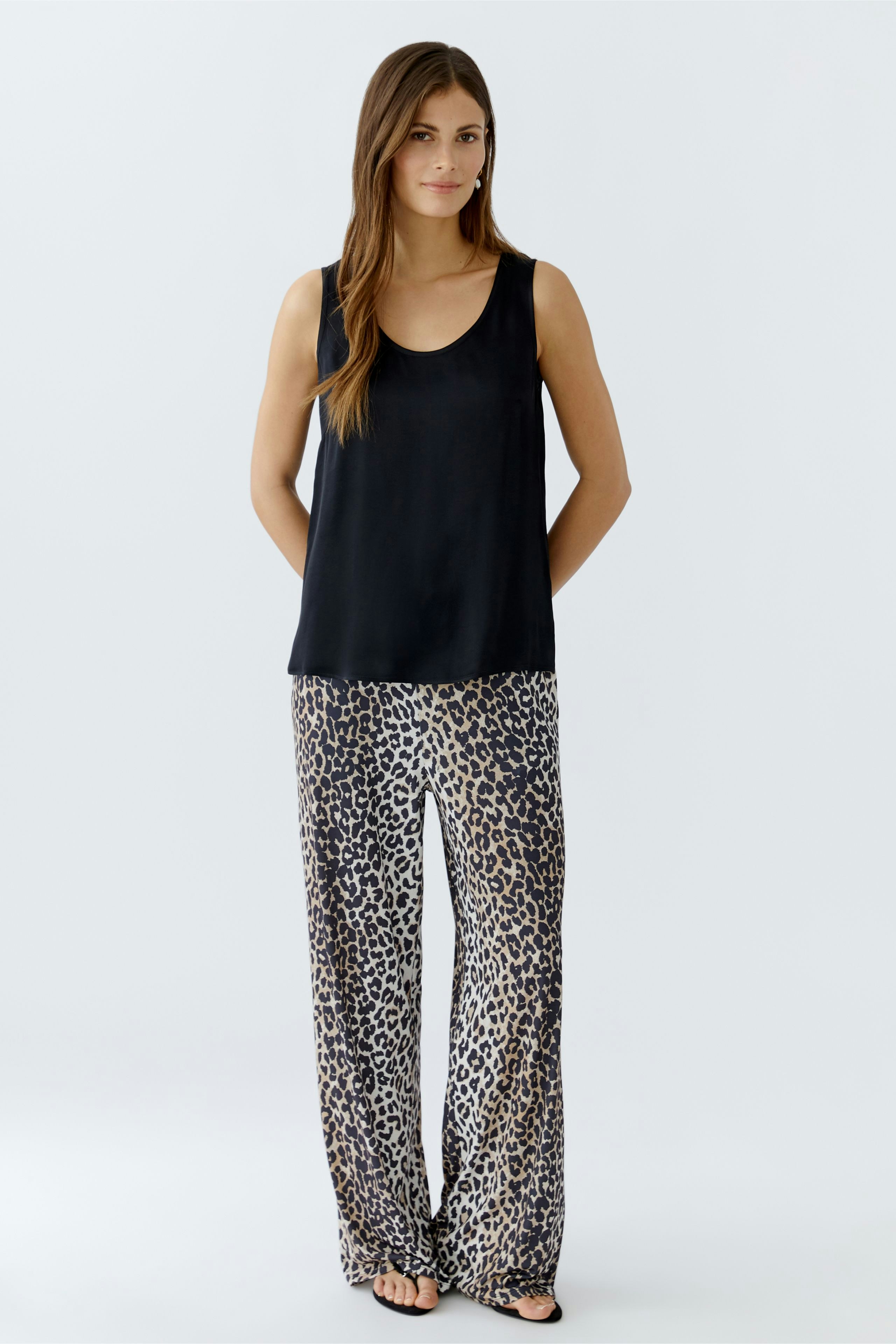 Casual women's pants: A woman in loose-fitting leopard print trousers and a black tank top.