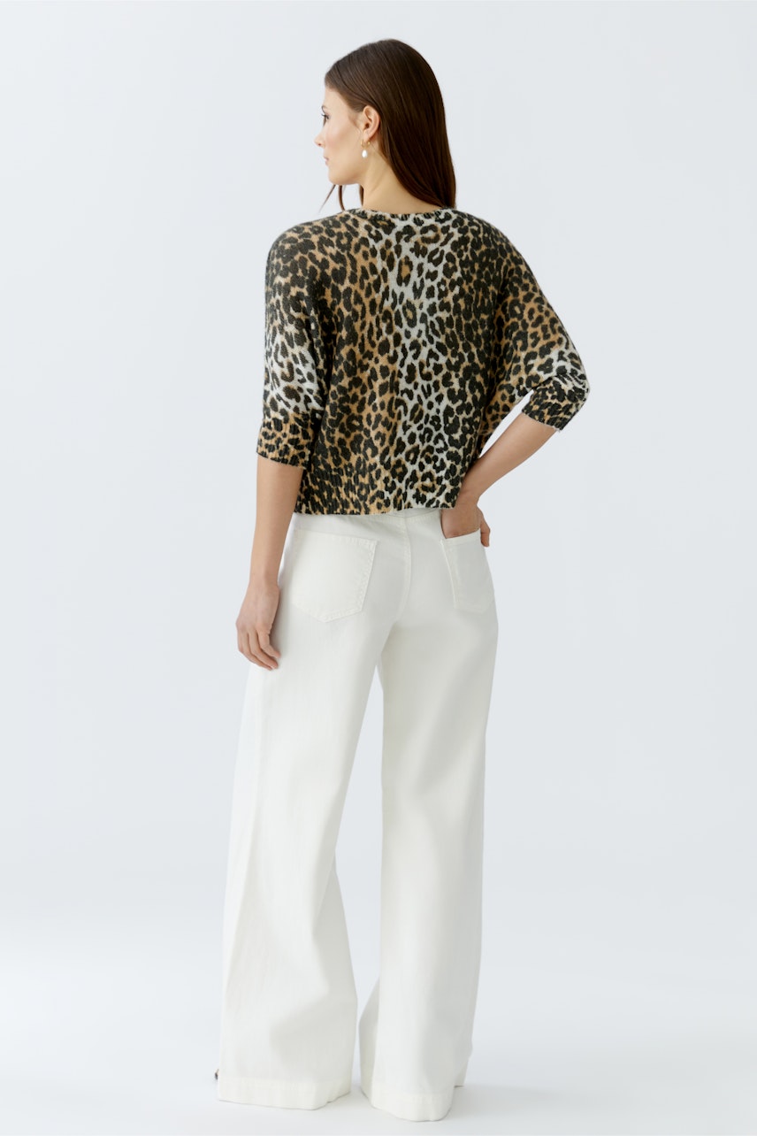 Casual women's cardigan: A woman in a leopard print cardigan with three-quarter sleeves and wide white pants.