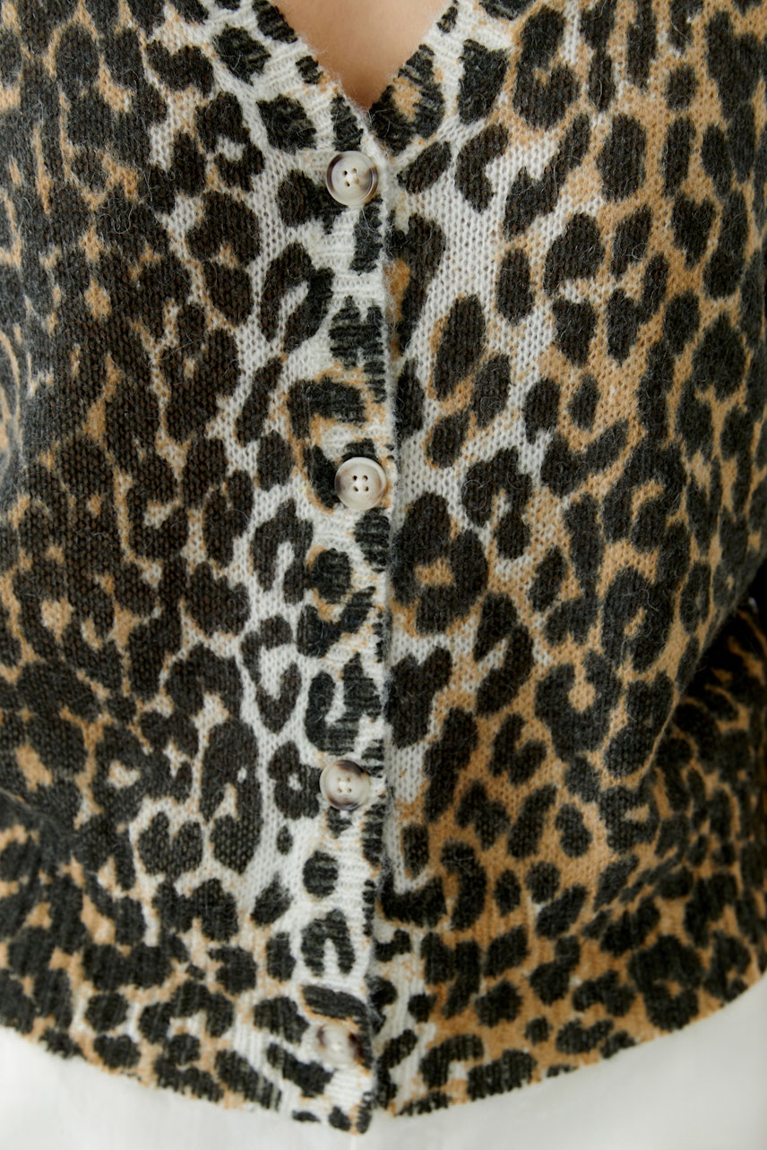 Casual women's cardigan: Close-up of a woman in a leopard print cardigan with buttons.