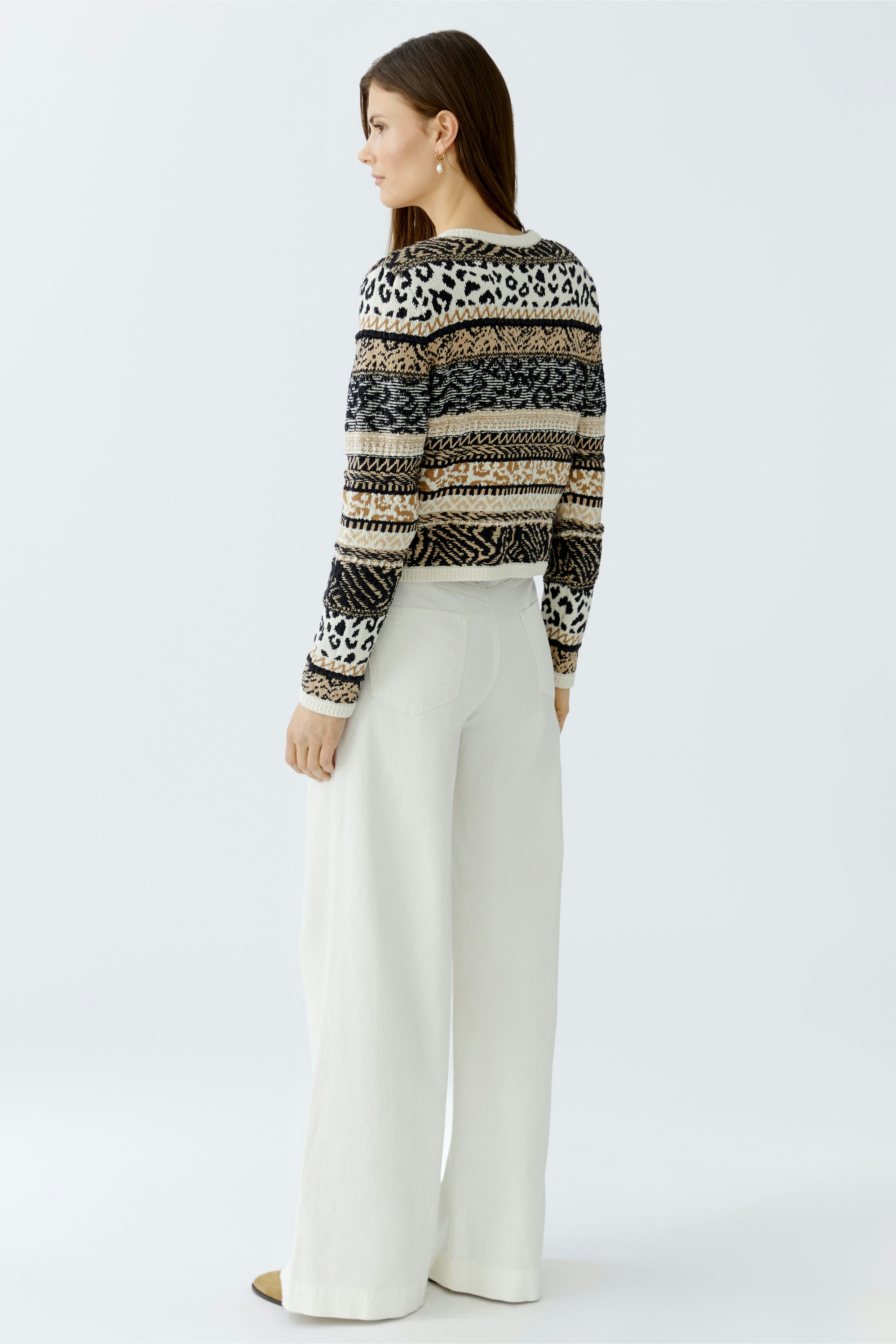 Casual women's cardigan: A woman in a patterned pullover with wide sleeves and relaxed-fit pants.