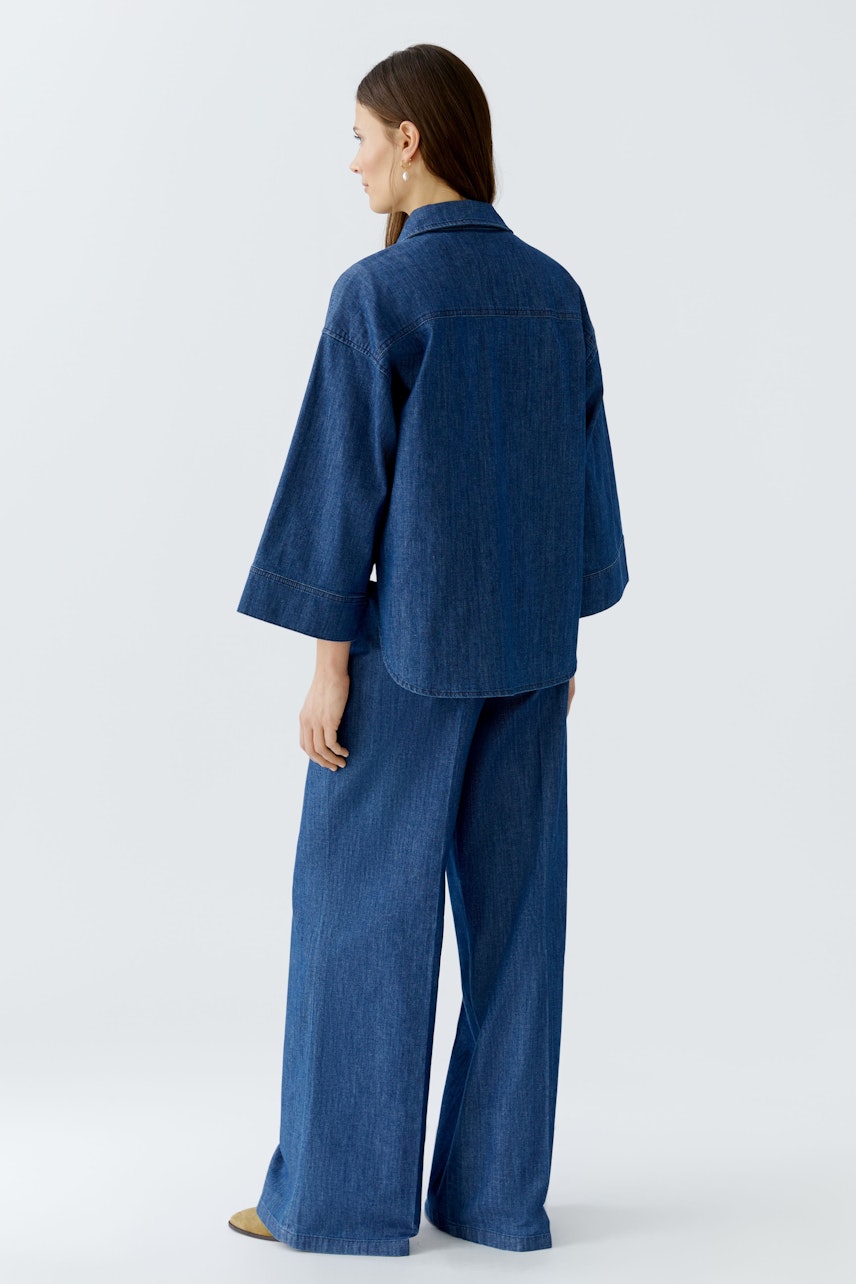 Lässige Jeansjacke: Frau trägt eine lockere, blaue Jeansjacke mit weitem Schnitt und lässigem Look.