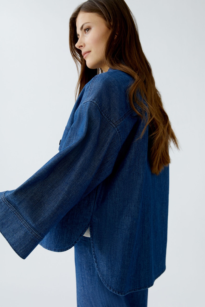Damen-Jeansjacke: Frau in lässiger, blauer Jeansjacke mit weitem Schnitt und langen Ärmeln.