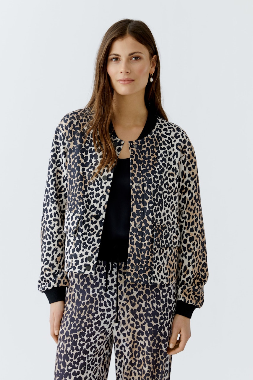 Trendy women's blouson: Woman in a leopard print bomber jacket, styled with matching pants.