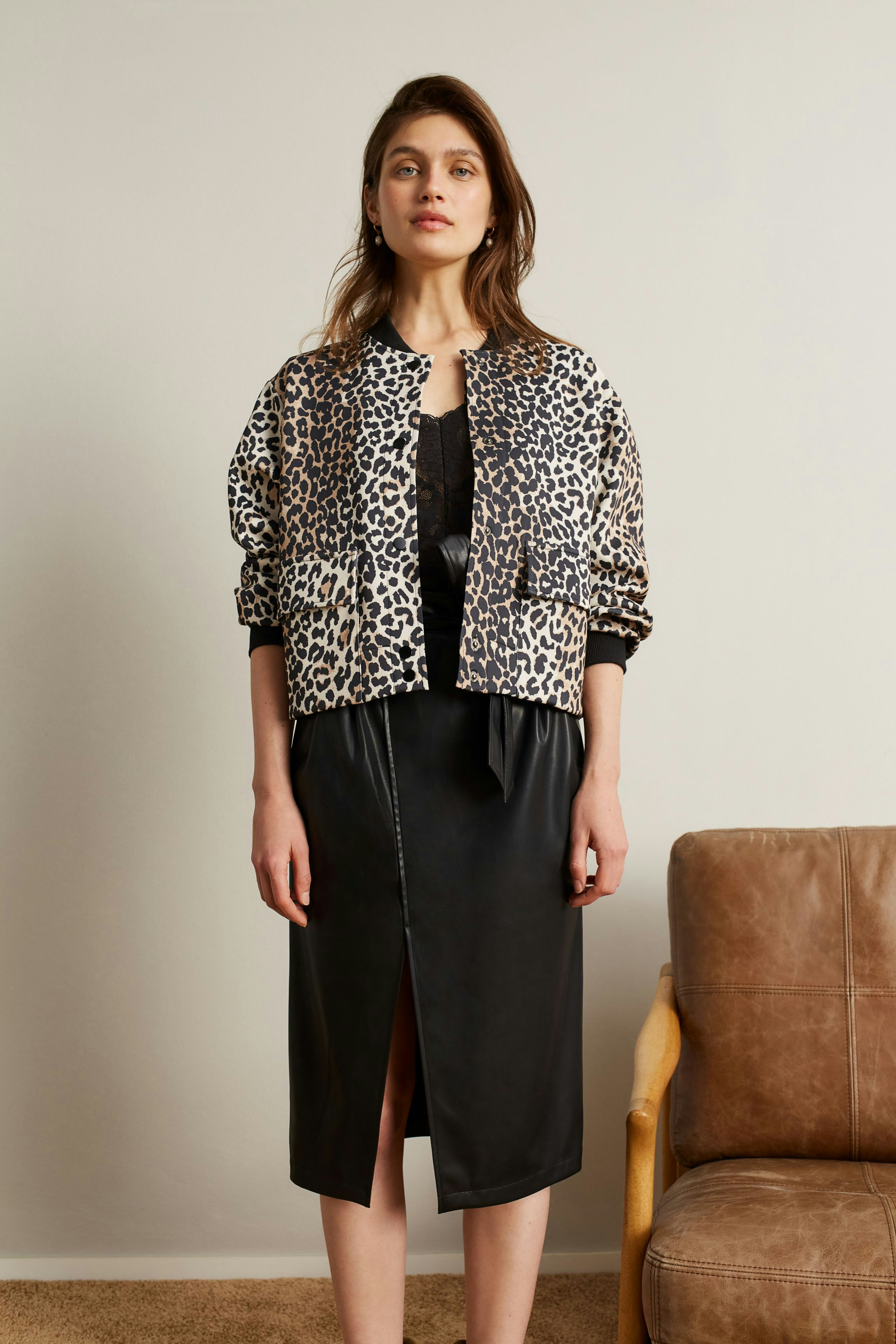 Trendy women's blouson: A woman in a leopard print bomber jacket over a black outfit, exuding casual style.