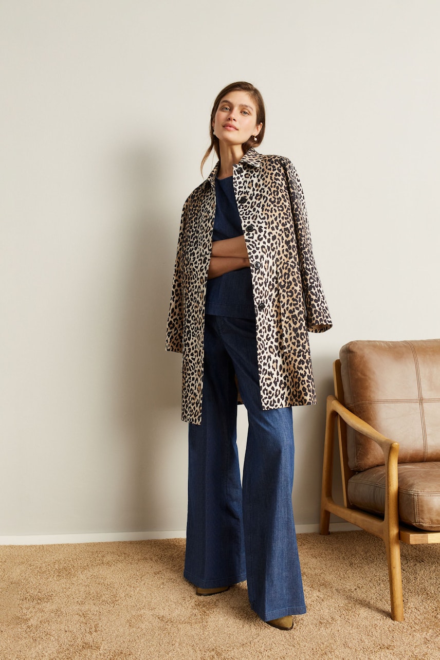 Stylish women's coat: A woman in a leopard print coat stands confidently, paired with wide-leg jeans.