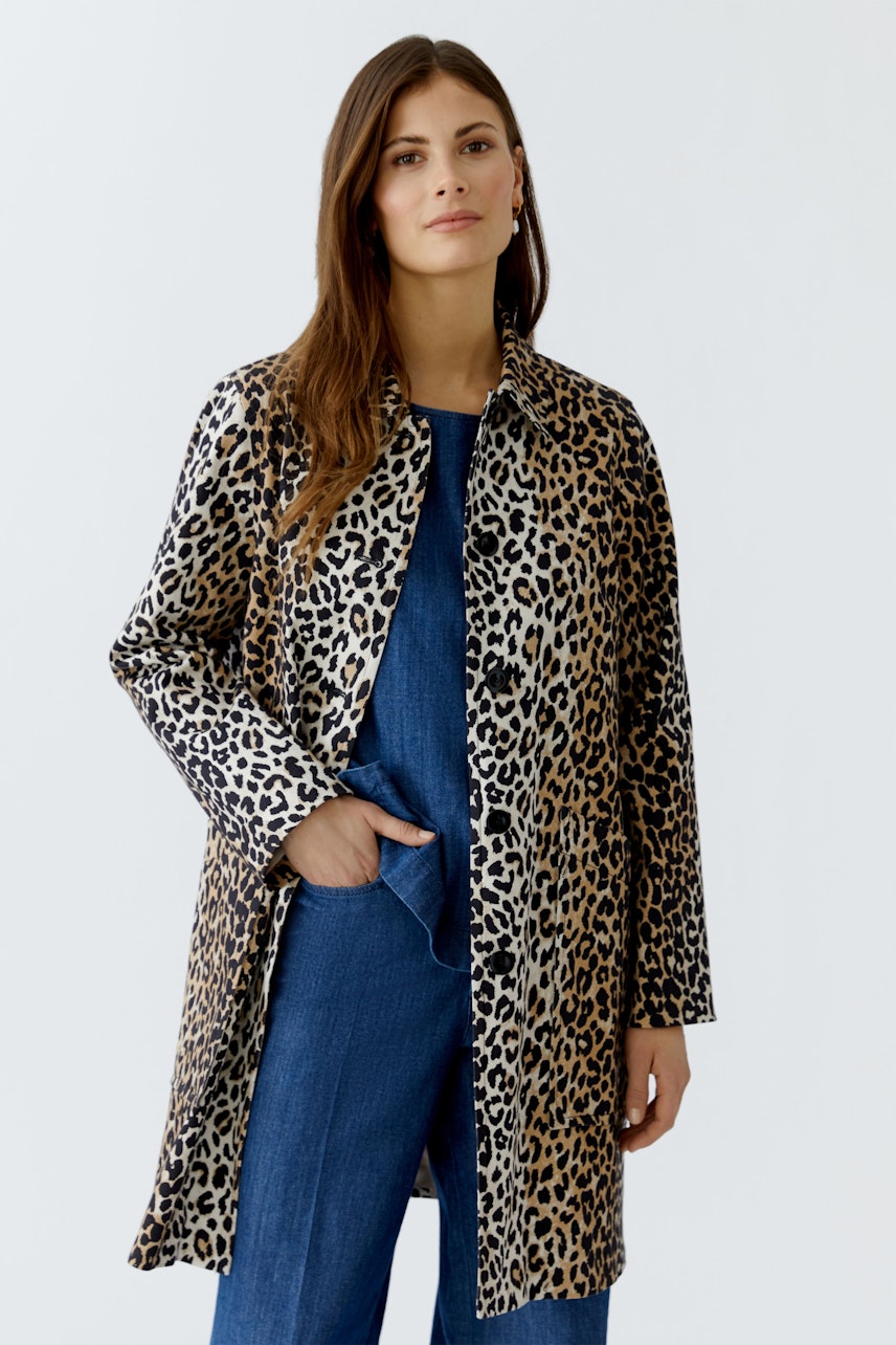Stylish women's coat: A woman in a leopard print coat stands confidently, showcasing a bold fashion choice.
