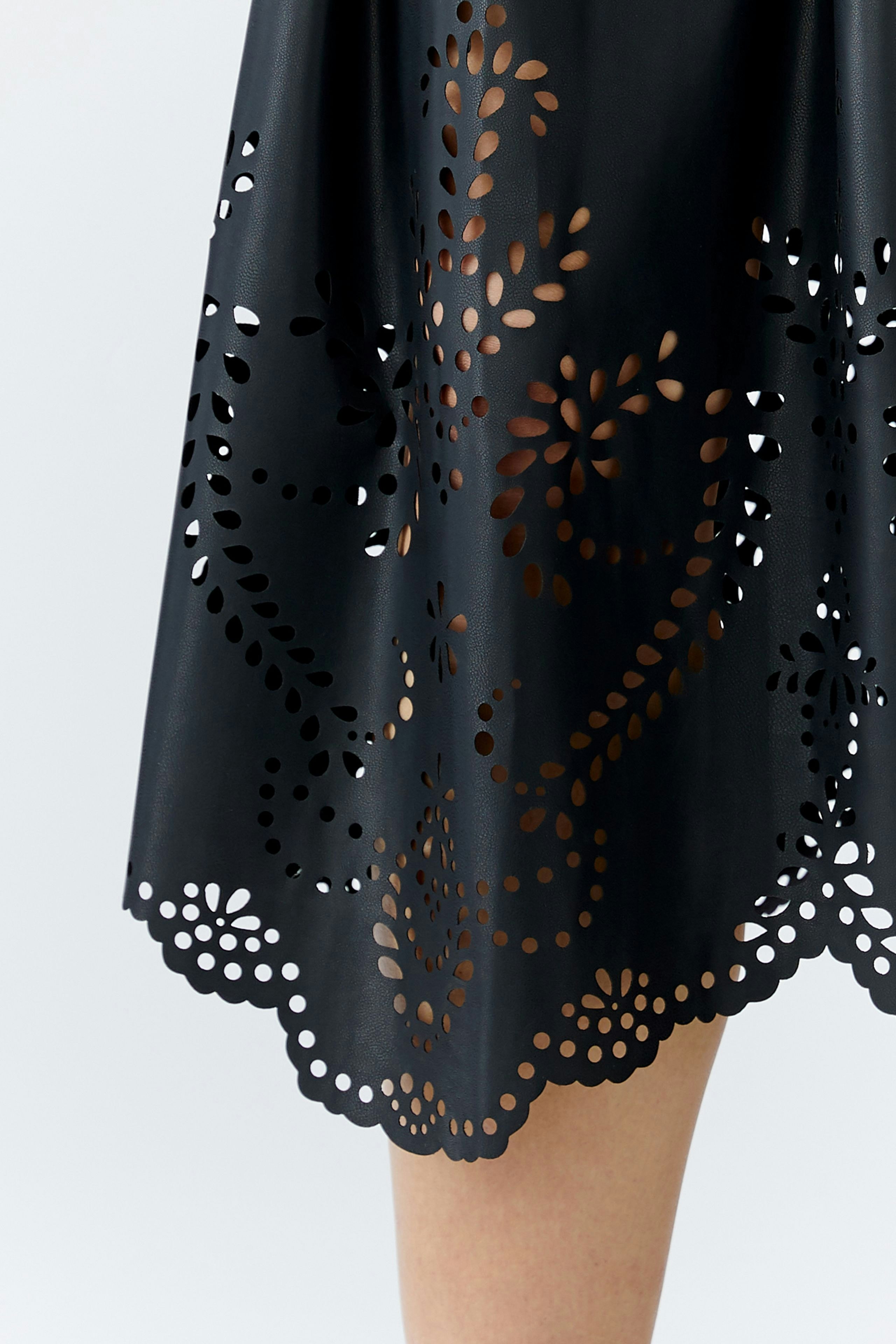 Schwarzer Lederimitatrock mit filigranen Ausschnitten und verspieltem Saum, ideal für den Alltag.