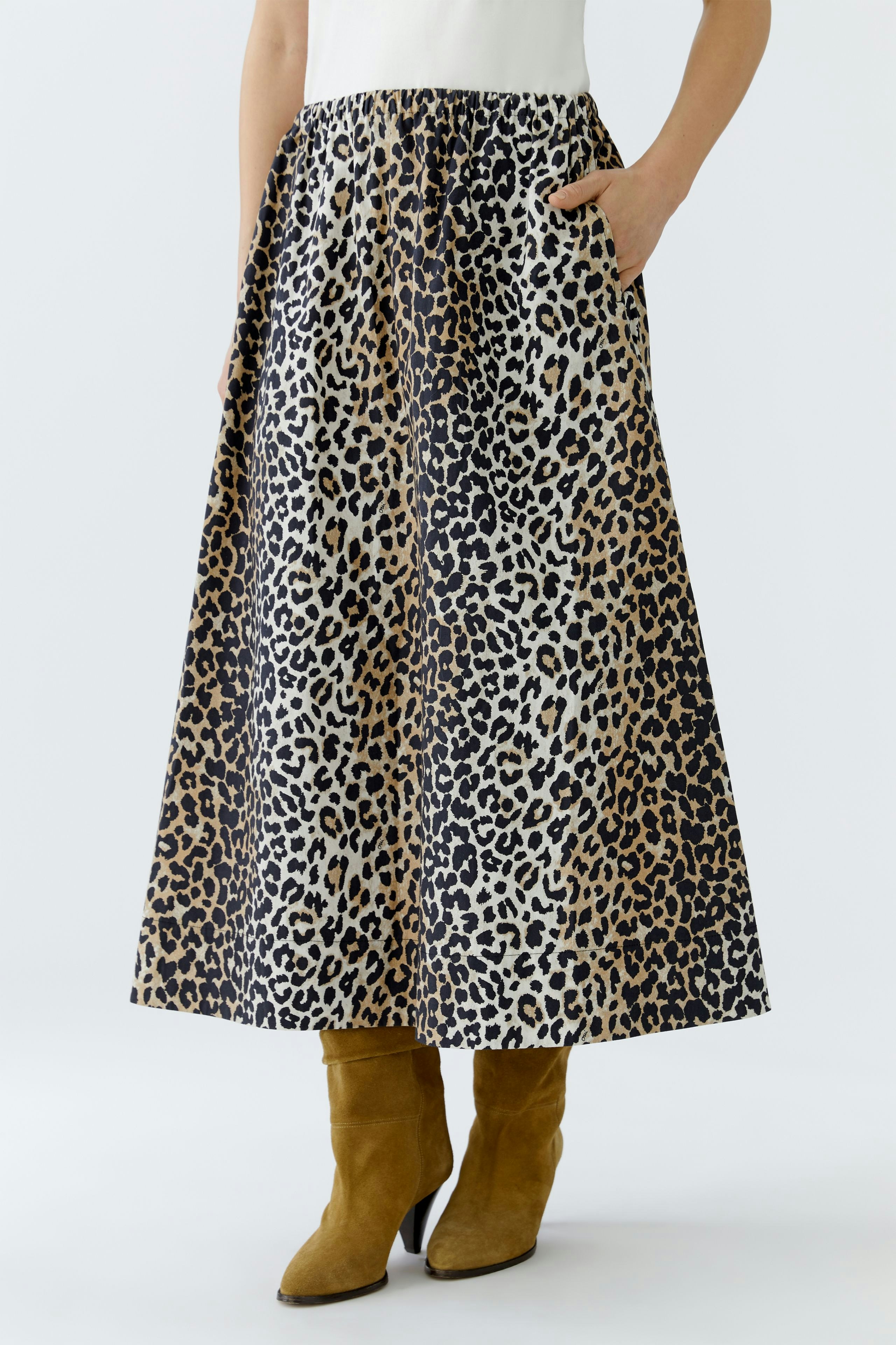 A-Linien-Rock: Frau trägt einen leopardenmuster Rock mit Taschen und kombiniert ihn mit braunen Stiefeln.