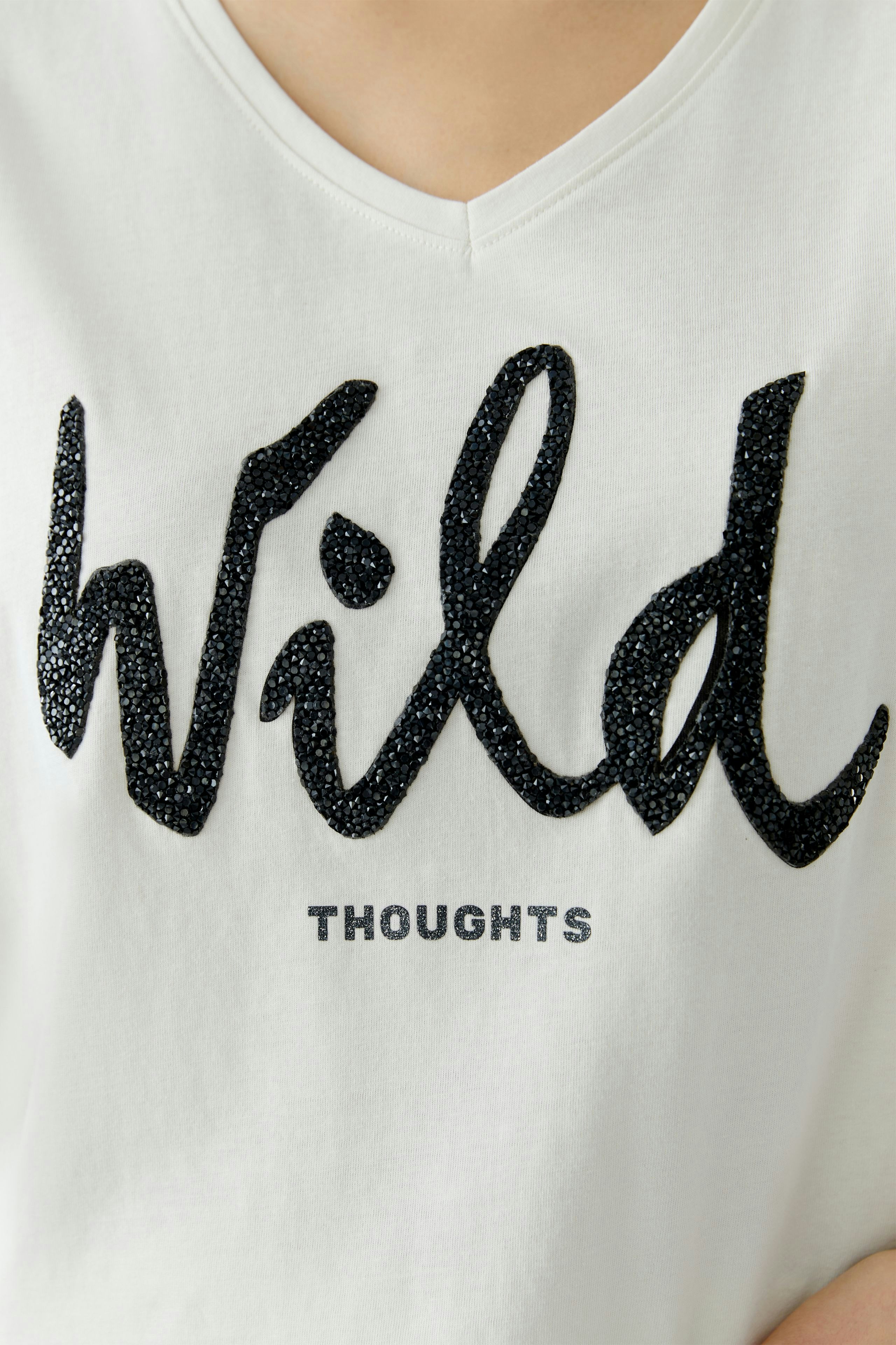 Casual women's T-shirt: A woman in a white tee with a bold black 'Wild' print and relaxed fit.